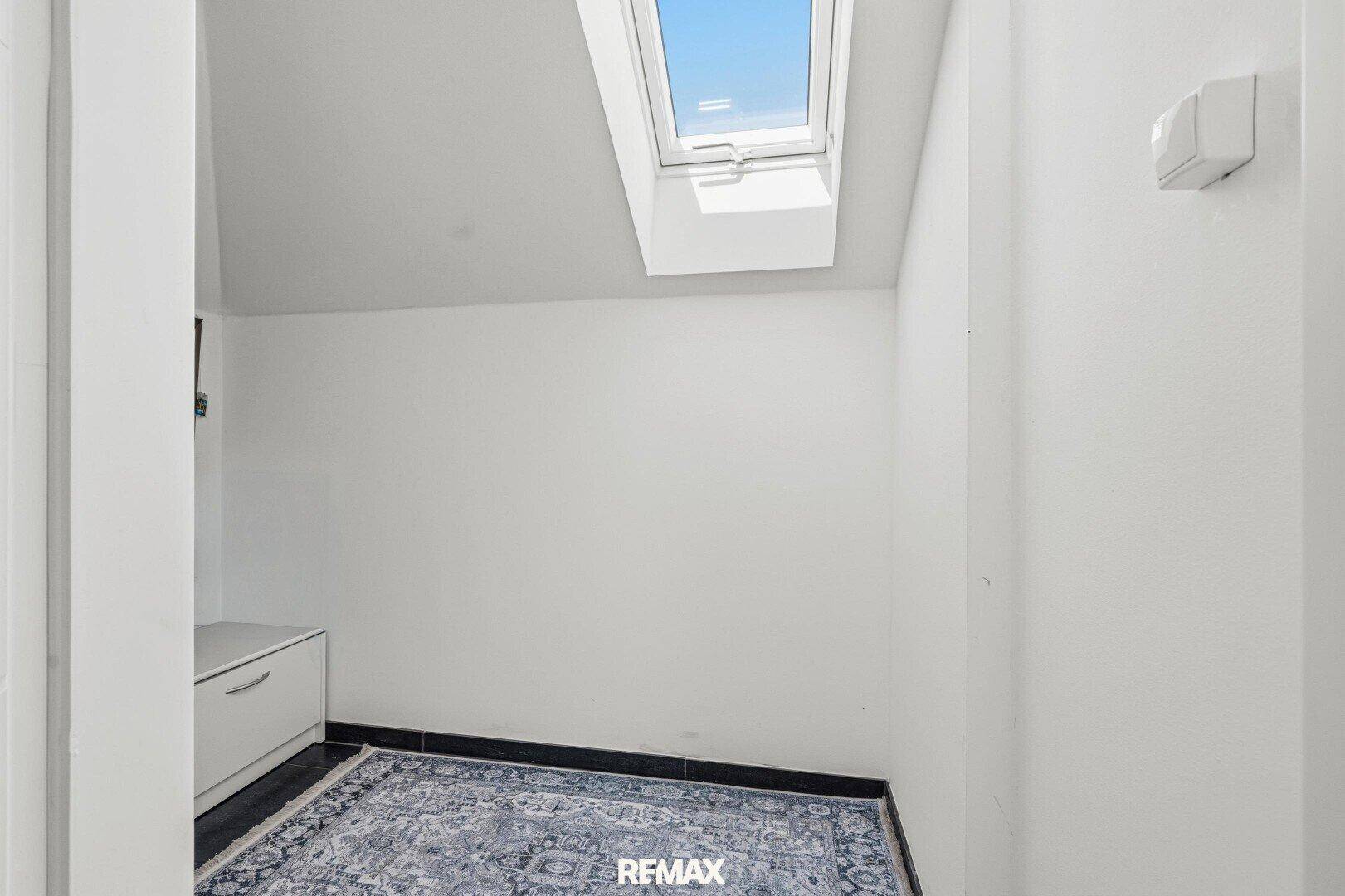 Kleiner Raum im Dachgeschoss mit Dachfenster und Teppichboden.