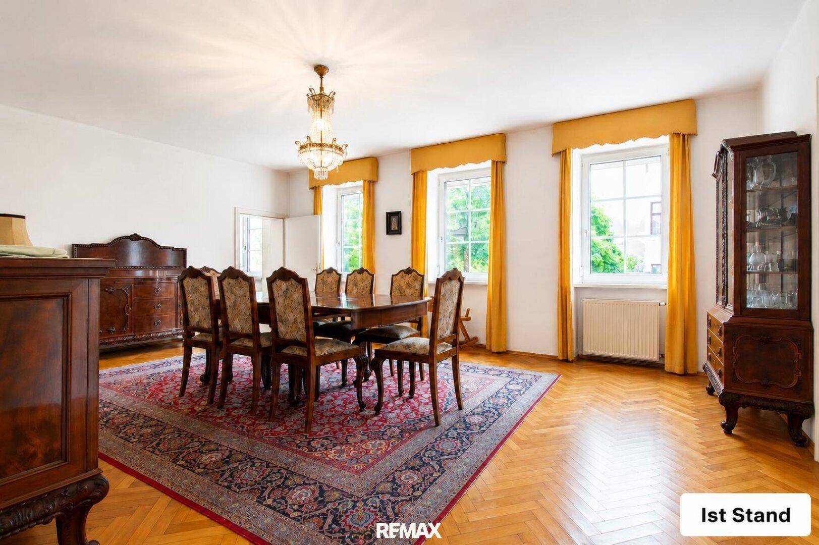Geräumiges Esszimmer mit klassischem Holztisch, passenden Stühlen und Fischgrätparkettboden.
