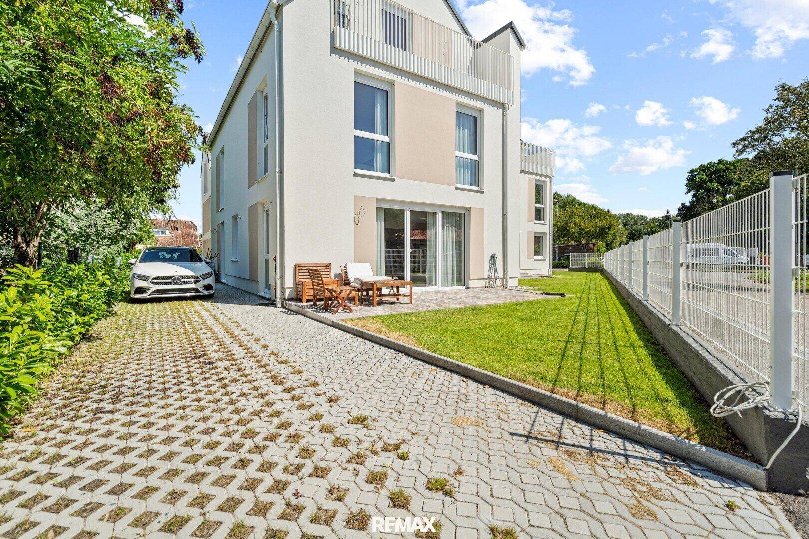 Gepflegter Gartenbereich mit Rasenfläche und Terrasse am Haus.