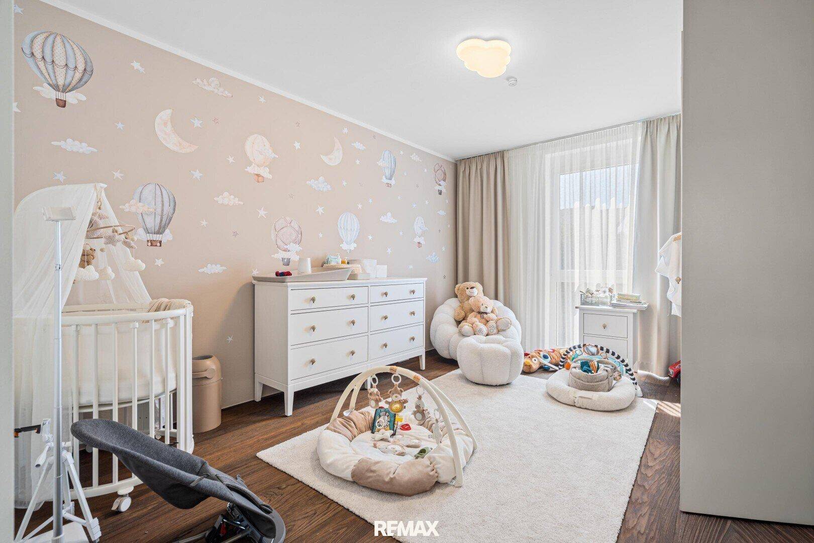 Liebevoll eingerichtetes Kinderzimmer mit Tapete, Holzboden und viel Tageslicht.