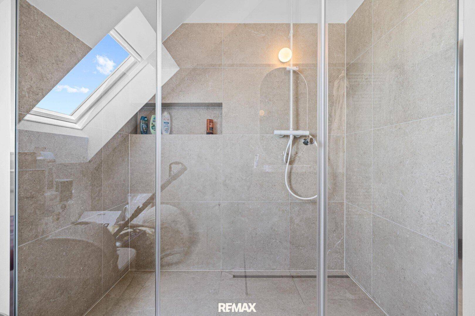 Modernes Badezimmer im Dachgeschoss mit Dusche und Dachfenster.