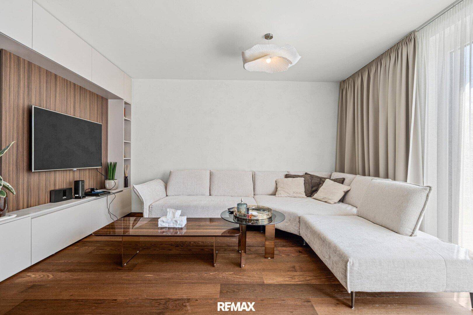 Gemütliches Wohnzimmer mit großem Ecksofa, Holzboden und modernem TV-Möbel.