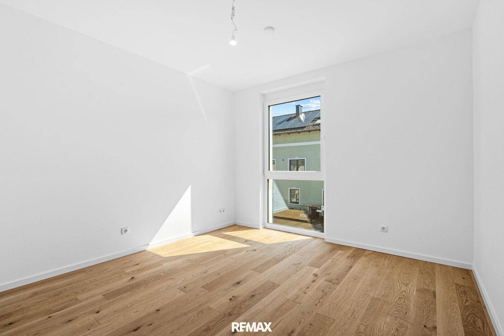 Geräumiges Schlafzimmer mit Eichenparkett und bodentiefem Fenster für viel Tageslicht.