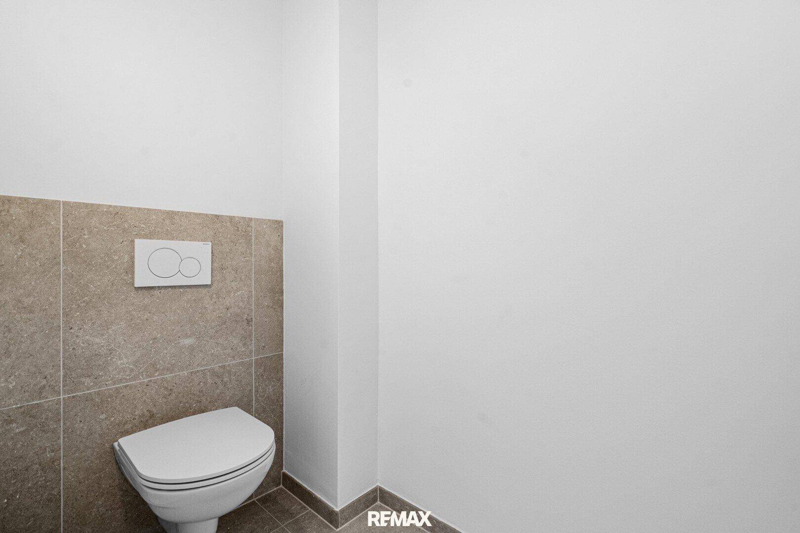 Modernes Gäste-WC mit Wand-WC und hellen Fliesen, schlicht und funktional gestaltet.