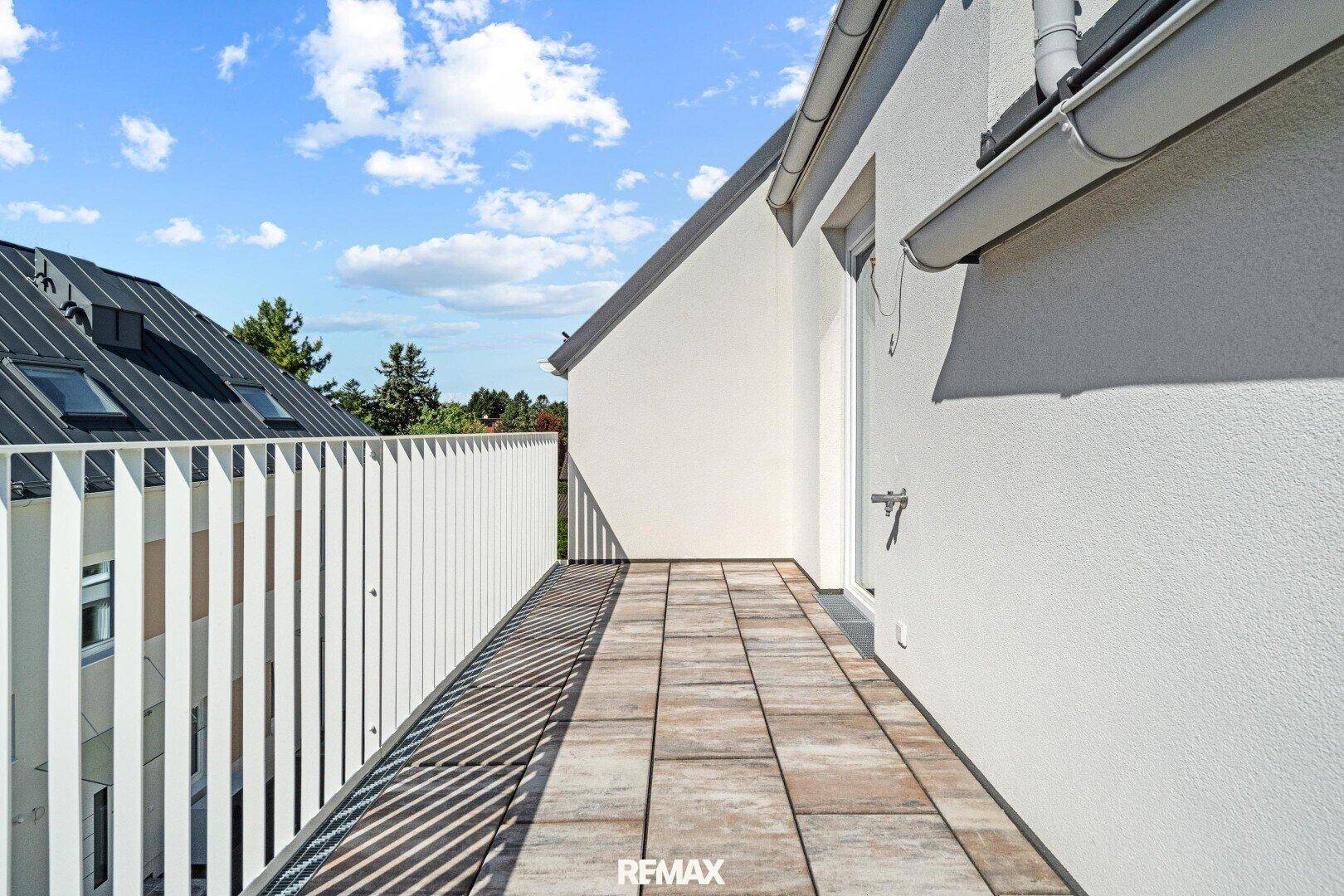 Heller Balkon mit Fliesenboden und modernem Geländer, ideal für entspannte Stunden im Freien.