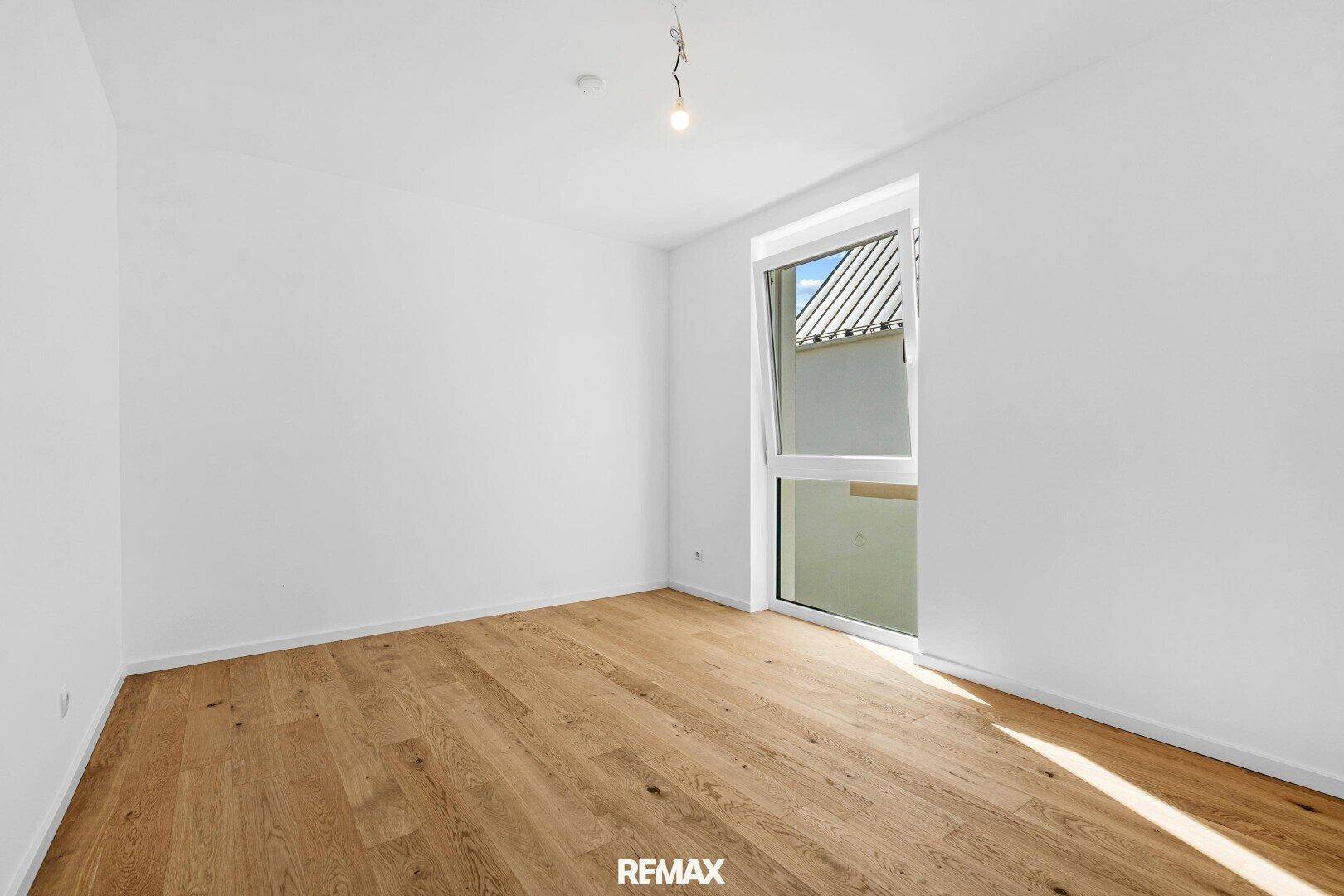 Helles Zimmer mit Parkettboden und einem großen Fenster, das sich zum Lüften öffnen lässt.