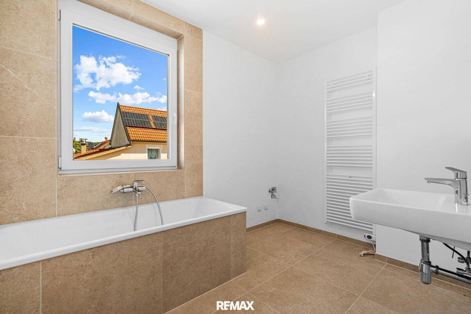 Modernes Badezimmer mit Badewanne, Einzelwaschbecken und beheiztem Handtuchhalter, Blick auf Dächer.