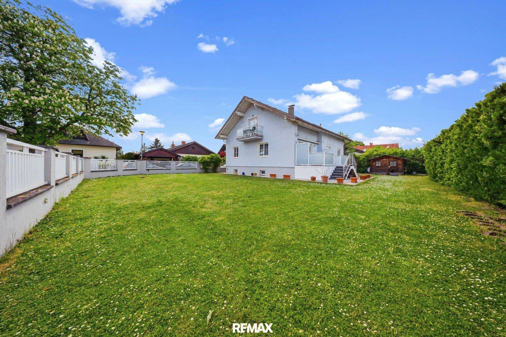 Großer, gepflegter Garten mit Rasenfläche und Hecke, ideal zum Entspannen.