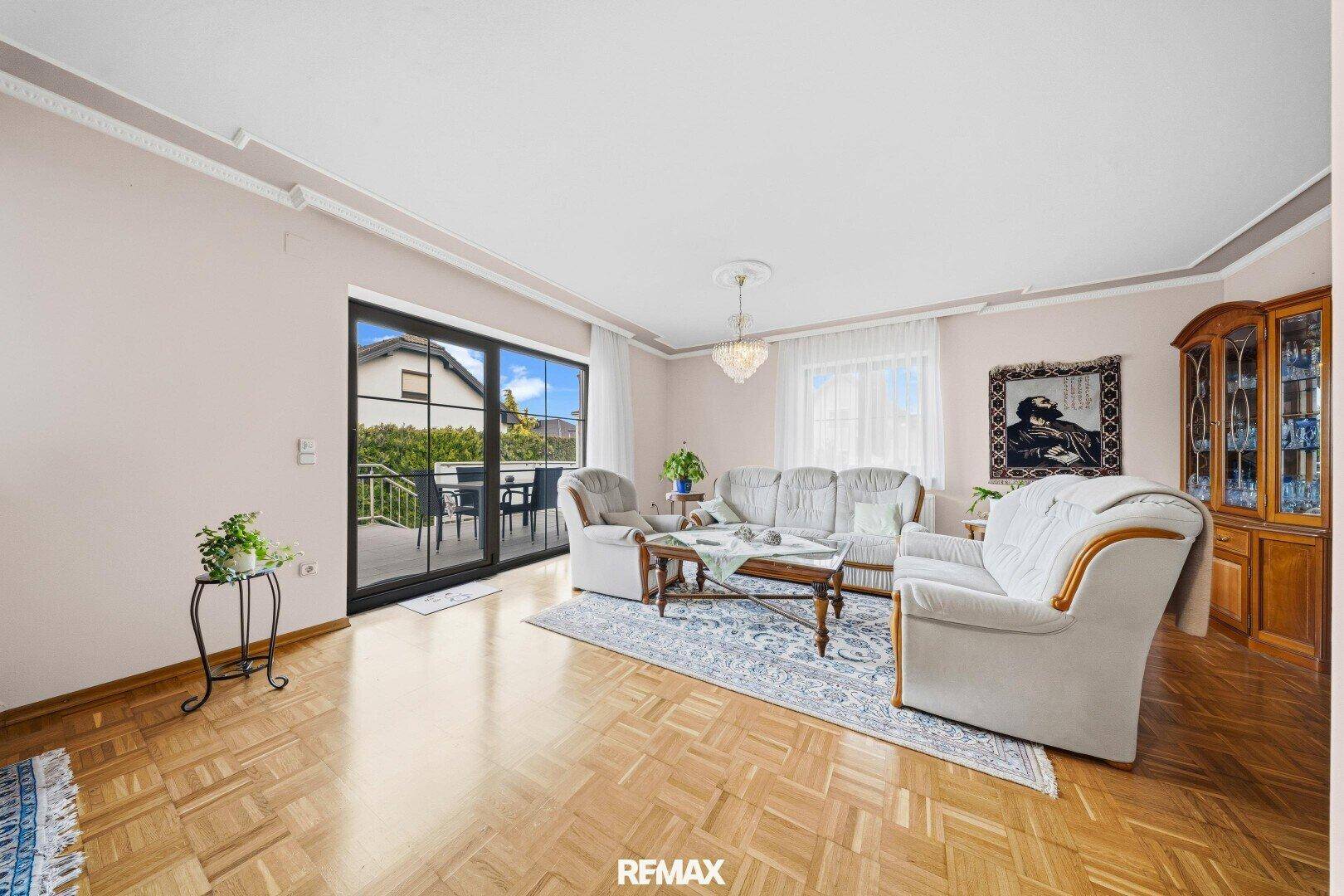 Helles Wohnzimmer mit Parkettboden, gemütlicher Sitzecke und Zugang zur Terrasse.