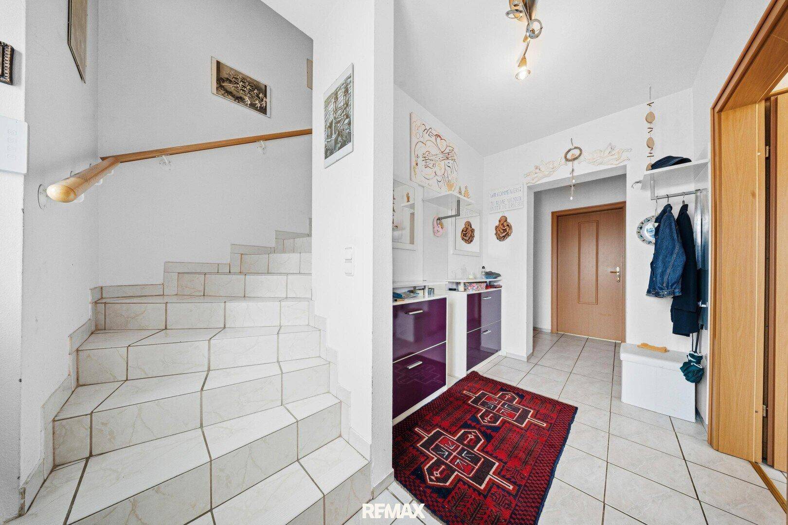 Eingangsbereich mit gefliester Treppe und Garderobe, hell und funktional.