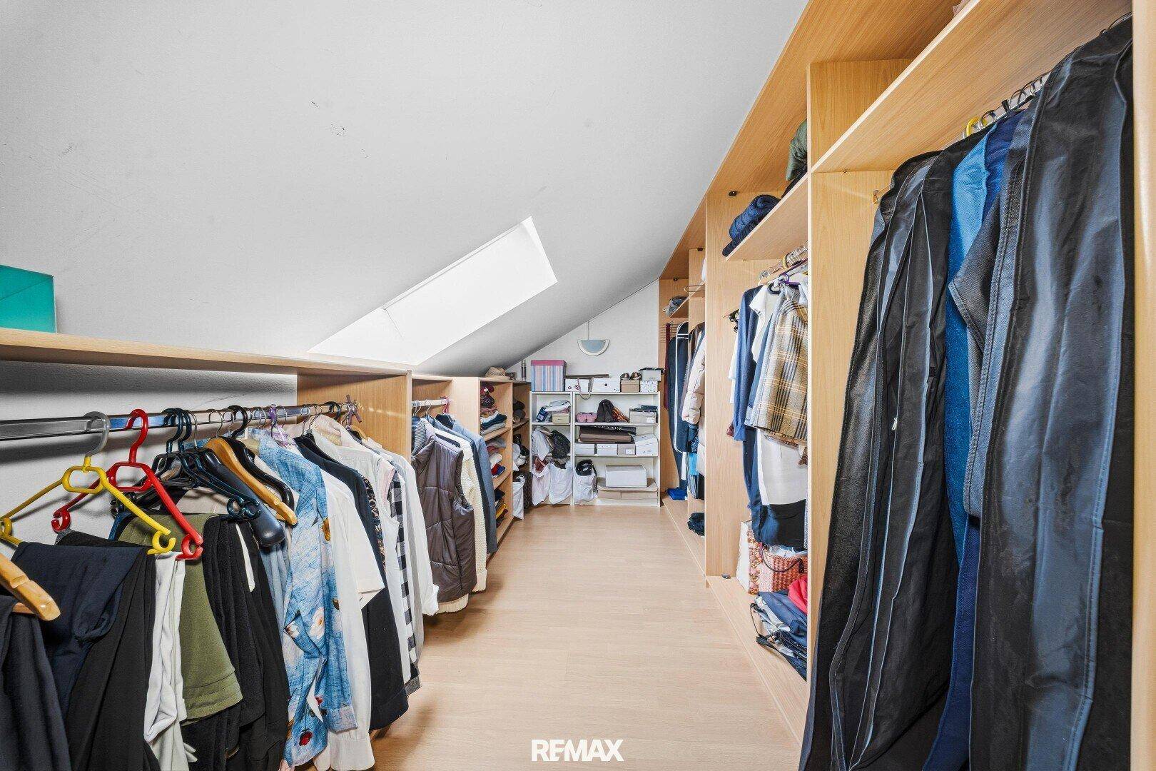Begehbarer Kleiderschrank im Dachgeschoss mit viel Stauraum und Dachfenster.