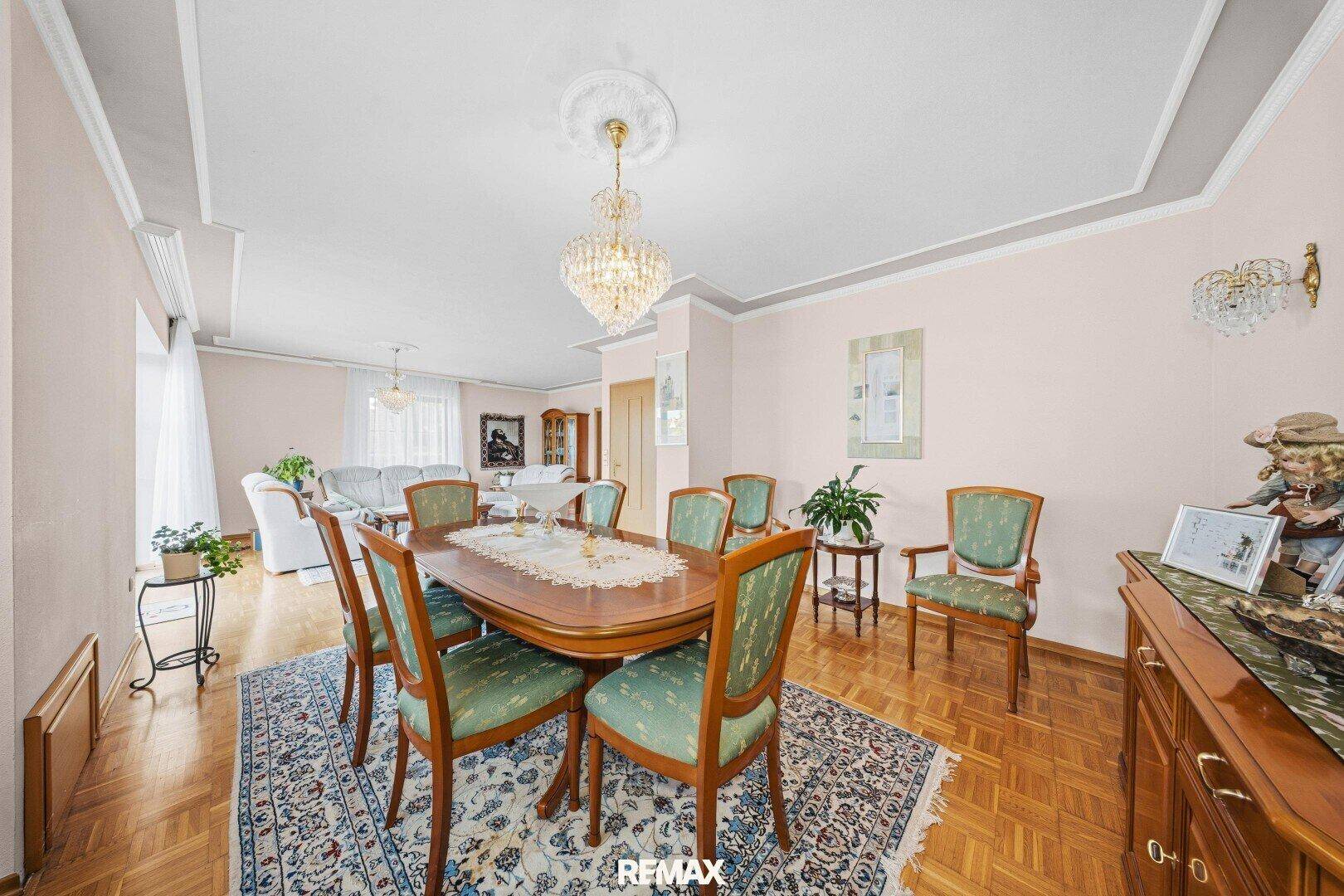 Klassischer Essbereich mit Holztisch, Stühlen und Kronleuchter, offen zum Wohnzimmer.