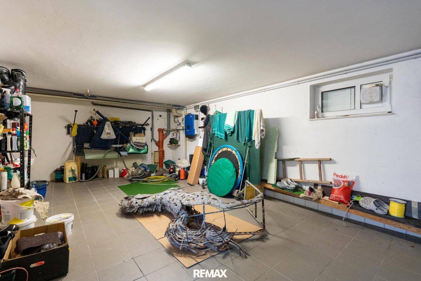Funktionale Garage mit Werkstattbereich, Regalen und einem kleinen Fenster.
