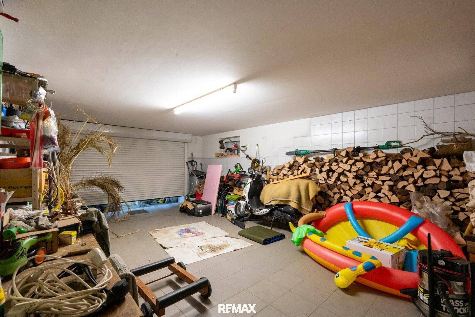 Geräumige Garage mit Stauraum, Werkzeugen und Holzstapel für den Winter.