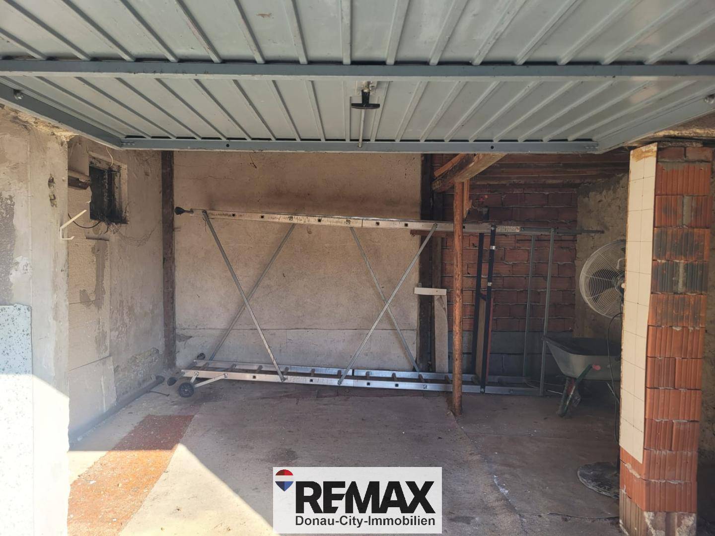 Leere Garage mit Betonboden, Ziegelwänden und Werkzeugen an der Seite.