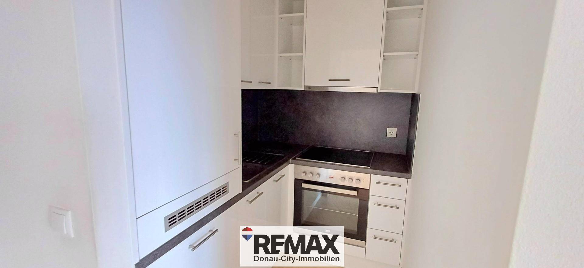 Kompakte Einbauküche mit weißen Schränken, Kochfeld und Backofen in modernem Design.