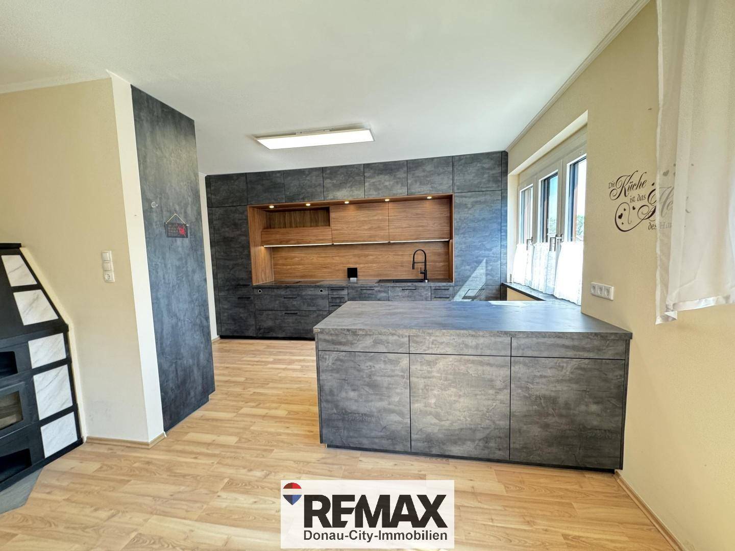 Moderne Einbauküche mit dunklen Fronten, Holzdetails und einer praktischen Kücheninsel.