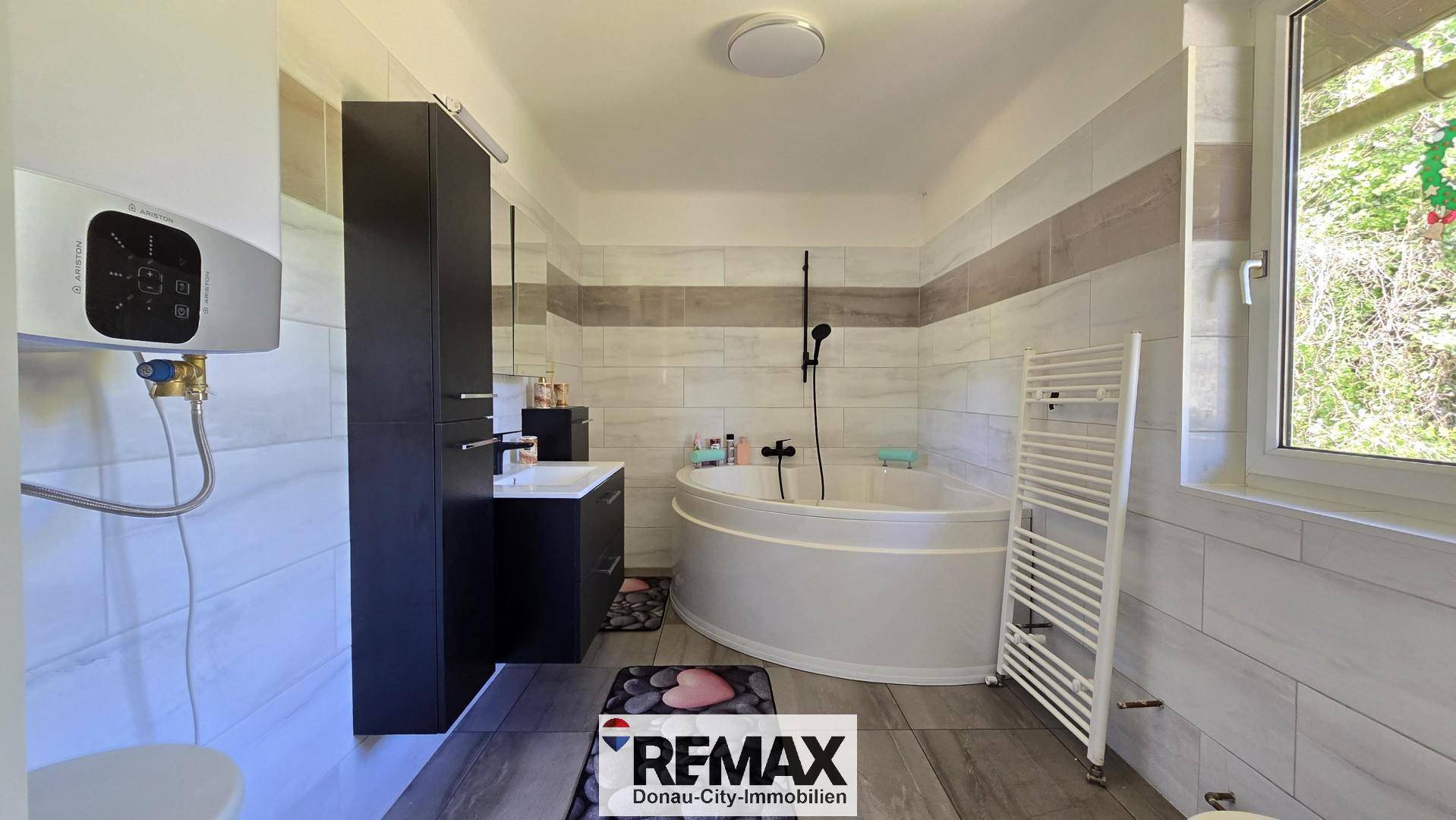 Modernes Badezimmer mit runder Badewanne, Waschtisch und Fenster.