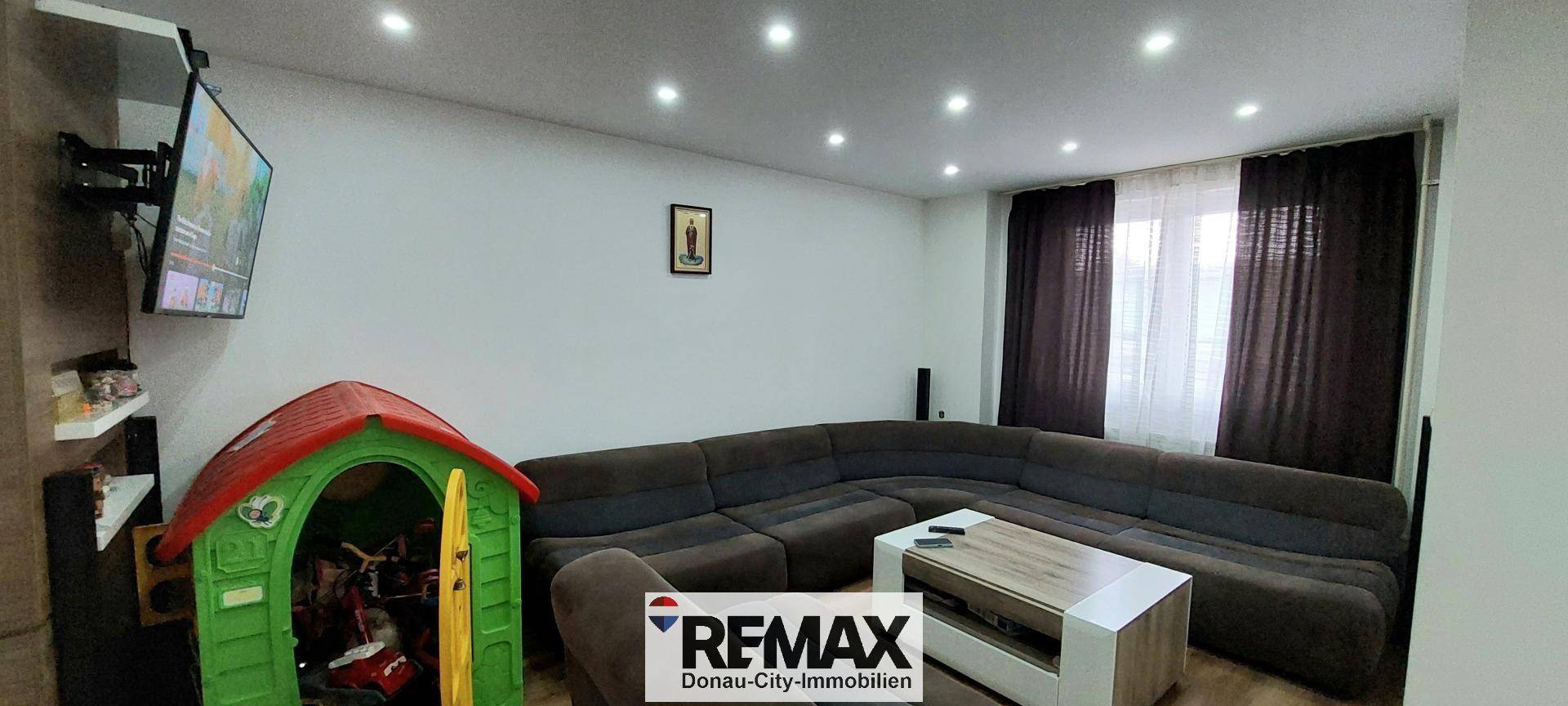 Gemütliches Wohnzimmer mit großem Sofa und Spielbereich für Kinder, hell und einladend.