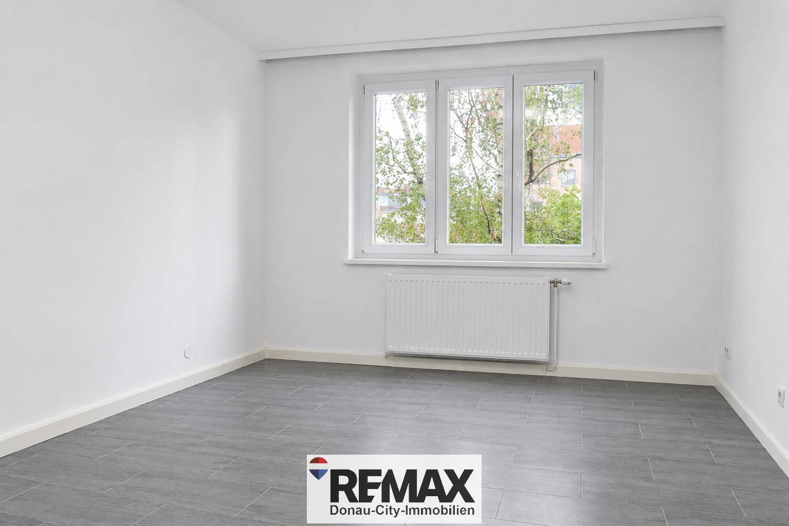 Leeres Schlafzimmer mit großen Fenstern und Fliesenboden, ideal für individuelle Einrichtung und Komfort.