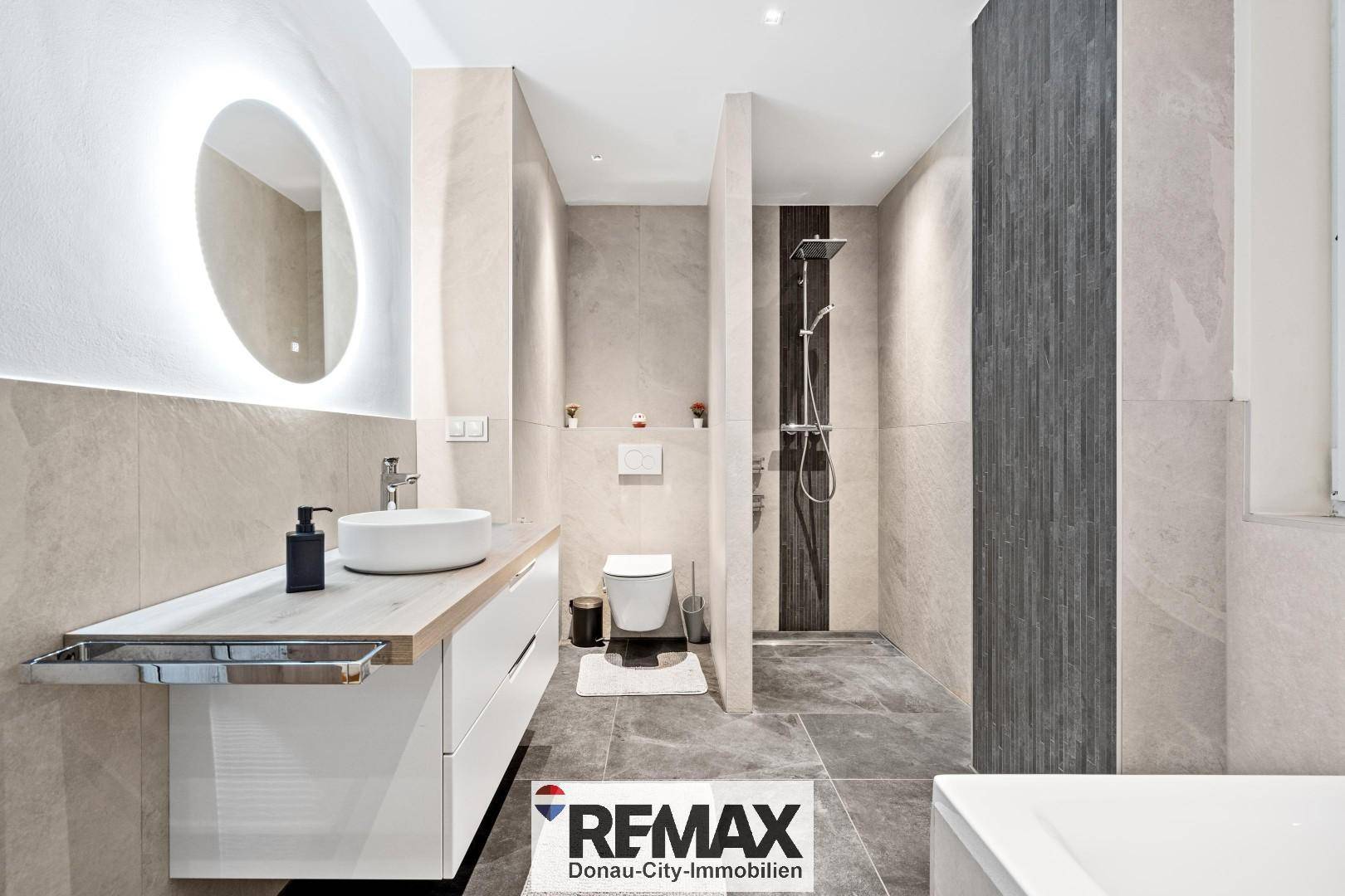 Modernes Badezimmer mit begehbarer Dusche, Wand-WC und beleuchtetem Spiegel.