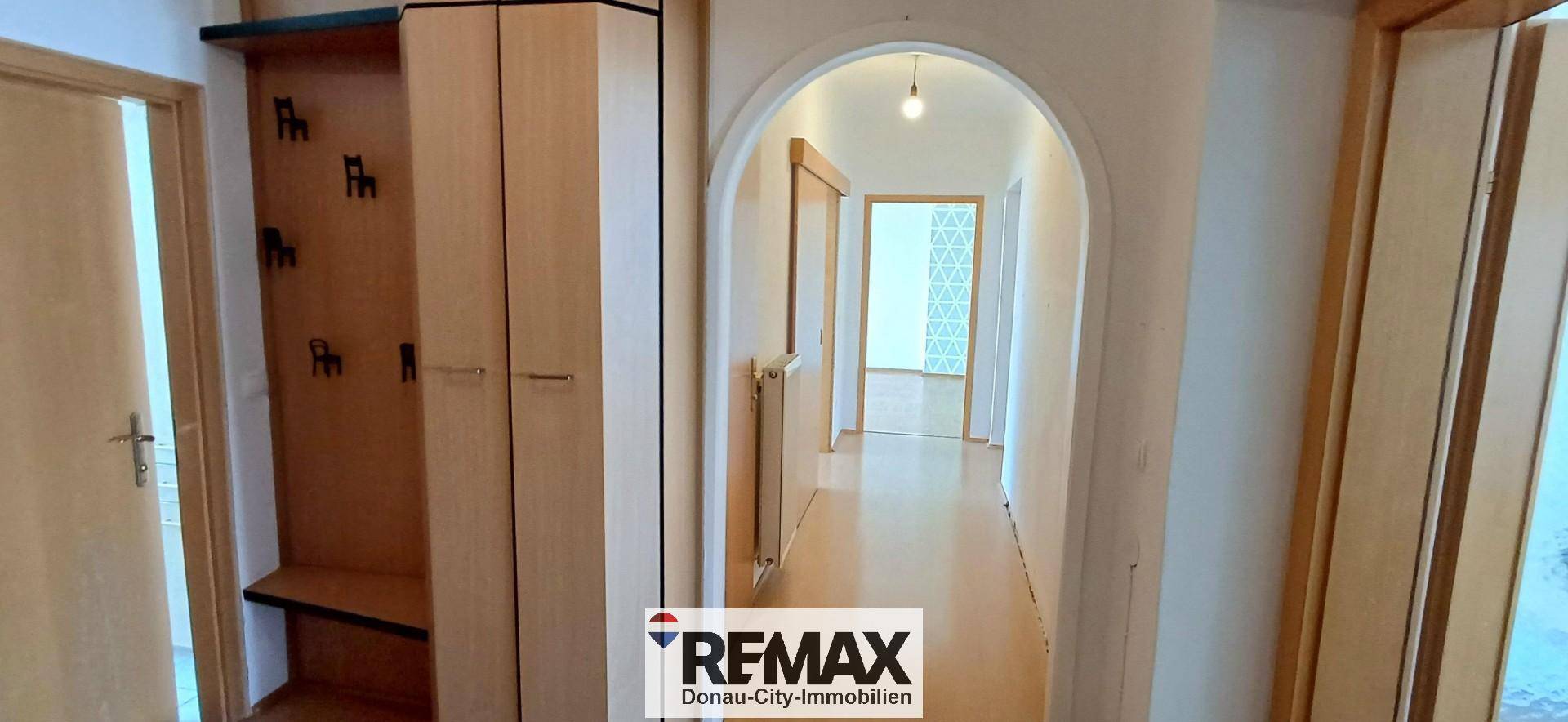 Heller Flur mit Holzboden und einem eleganten Rundbogen, der zu weiteren Räumen führt.