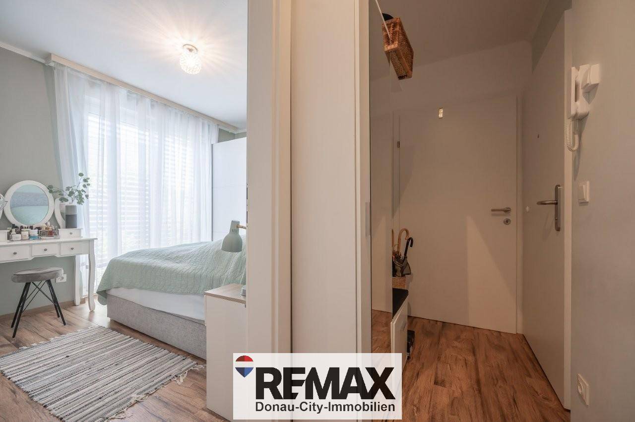 Helles Schlafzimmer mit modernem Bett, Schminktisch und Zugang zum Flur.