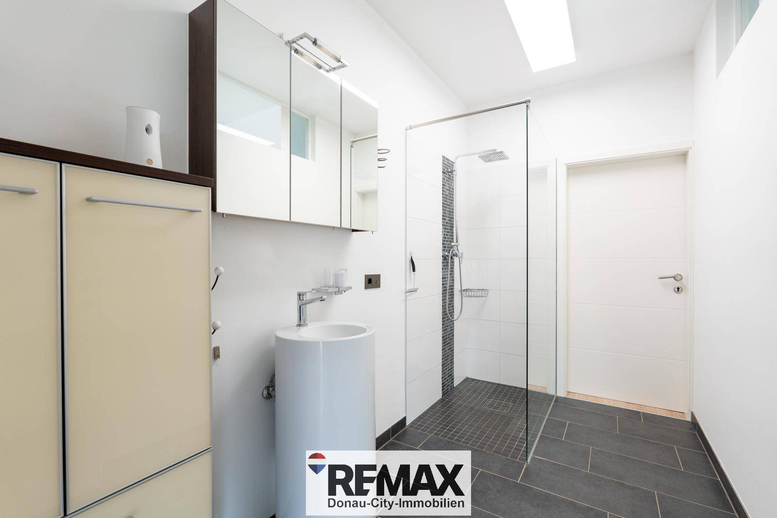 Modernes Badezimmer mit ebenerdiger Dusche, Standwaschbecken und Spiegelschrank.