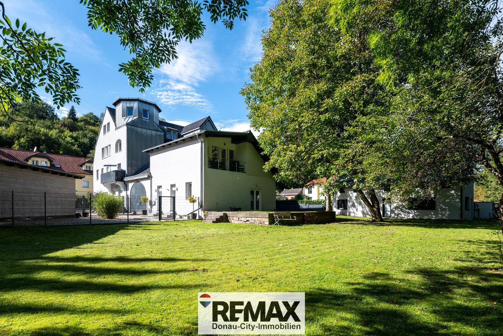 Großzügiger Gartenbereich mit altem Baumbestand und Blick auf das Mehrfamilienhaus.