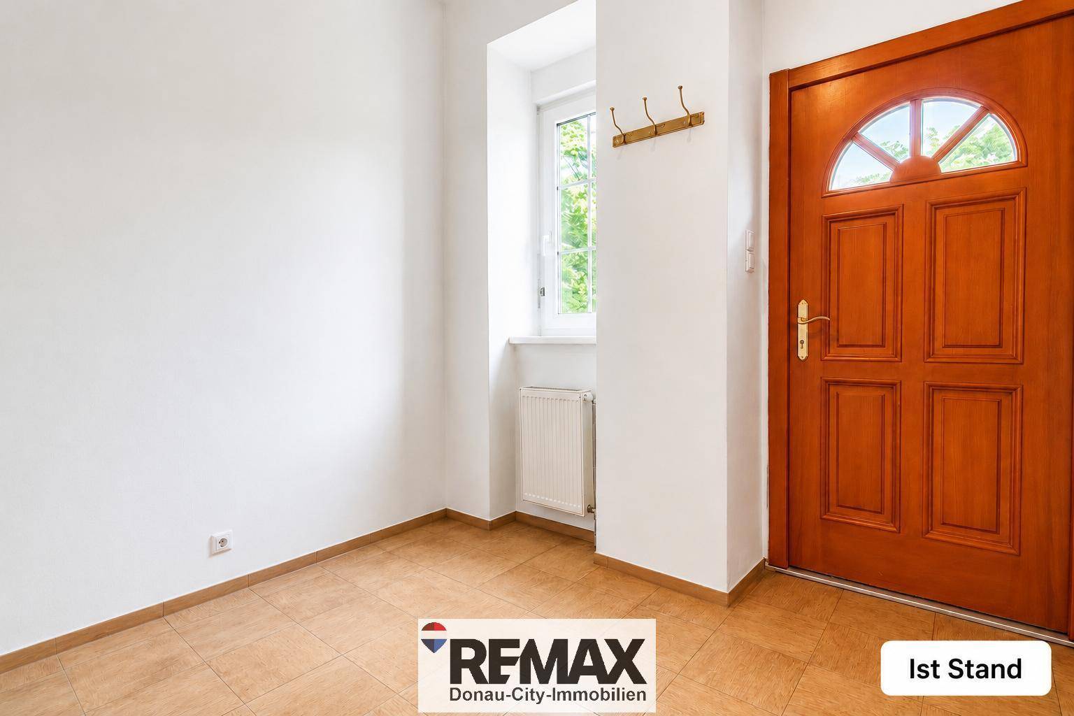 Heller Eingangsbereich mit Fliesenboden und Holztür, unmöbliert und funktional.