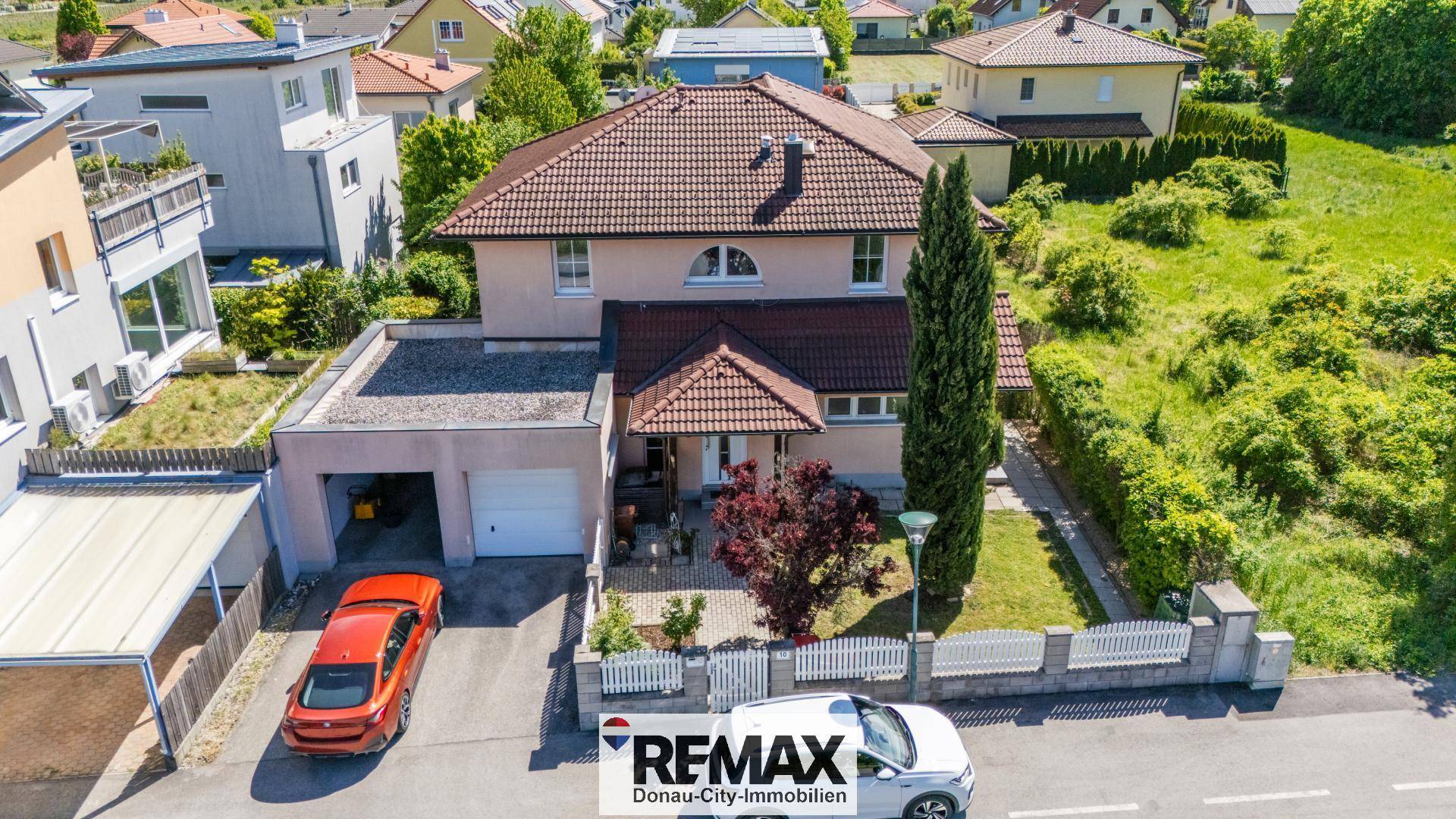 Luftaufnahme eines Einfamilienhauses mit Garage, Vorgarten und gepflegter Zufahrt.
