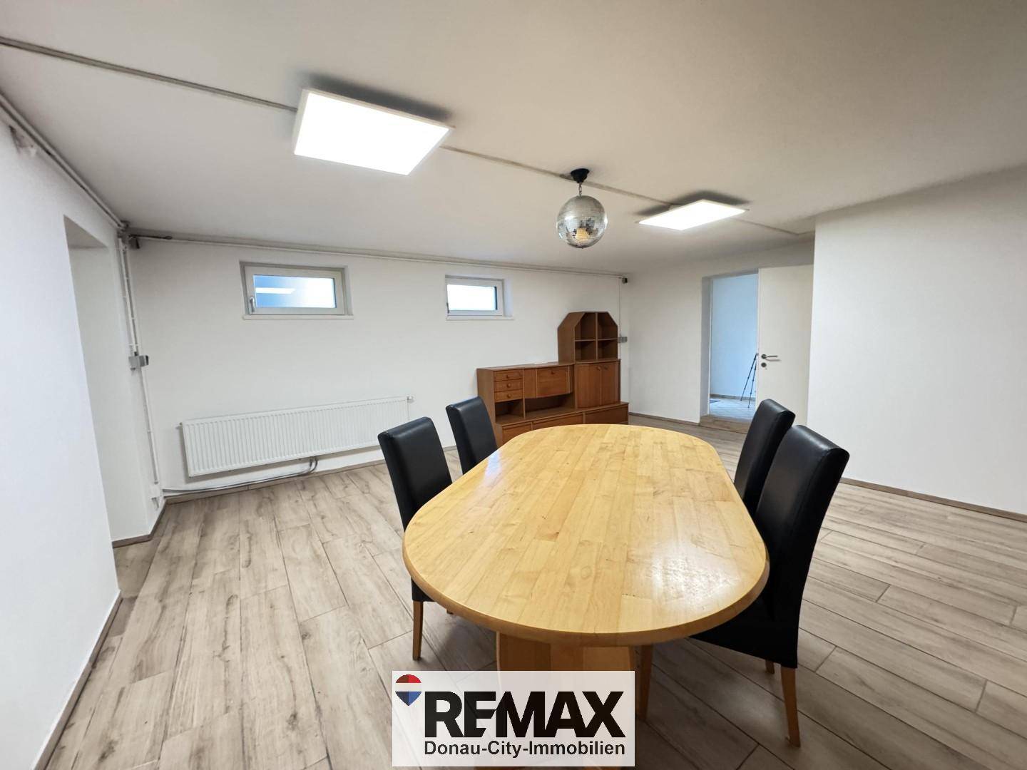 Esszimmer mit Holztisch, dunklen Stühlen und einem auffälligen Deckenlicht, ideal für Mahlzeiten.