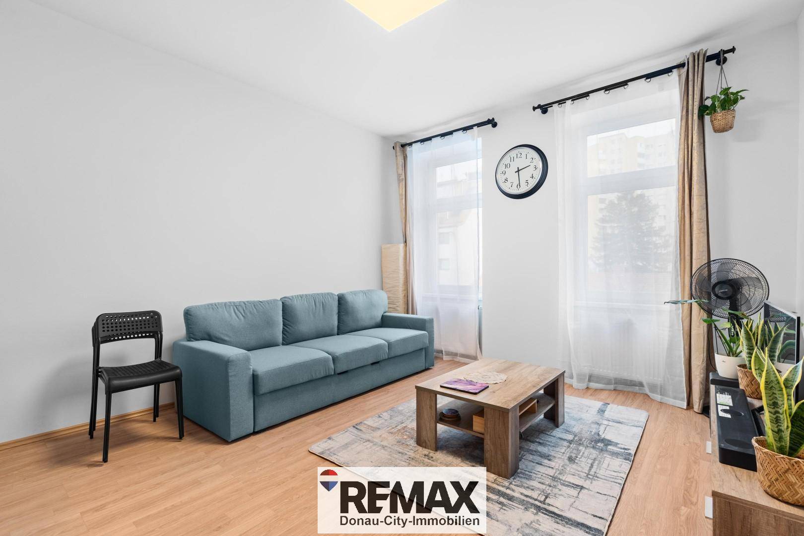 Helles Wohnzimmer mit beigem Teppich, blauem Sofa und einem Couchtisch aus Holz.
