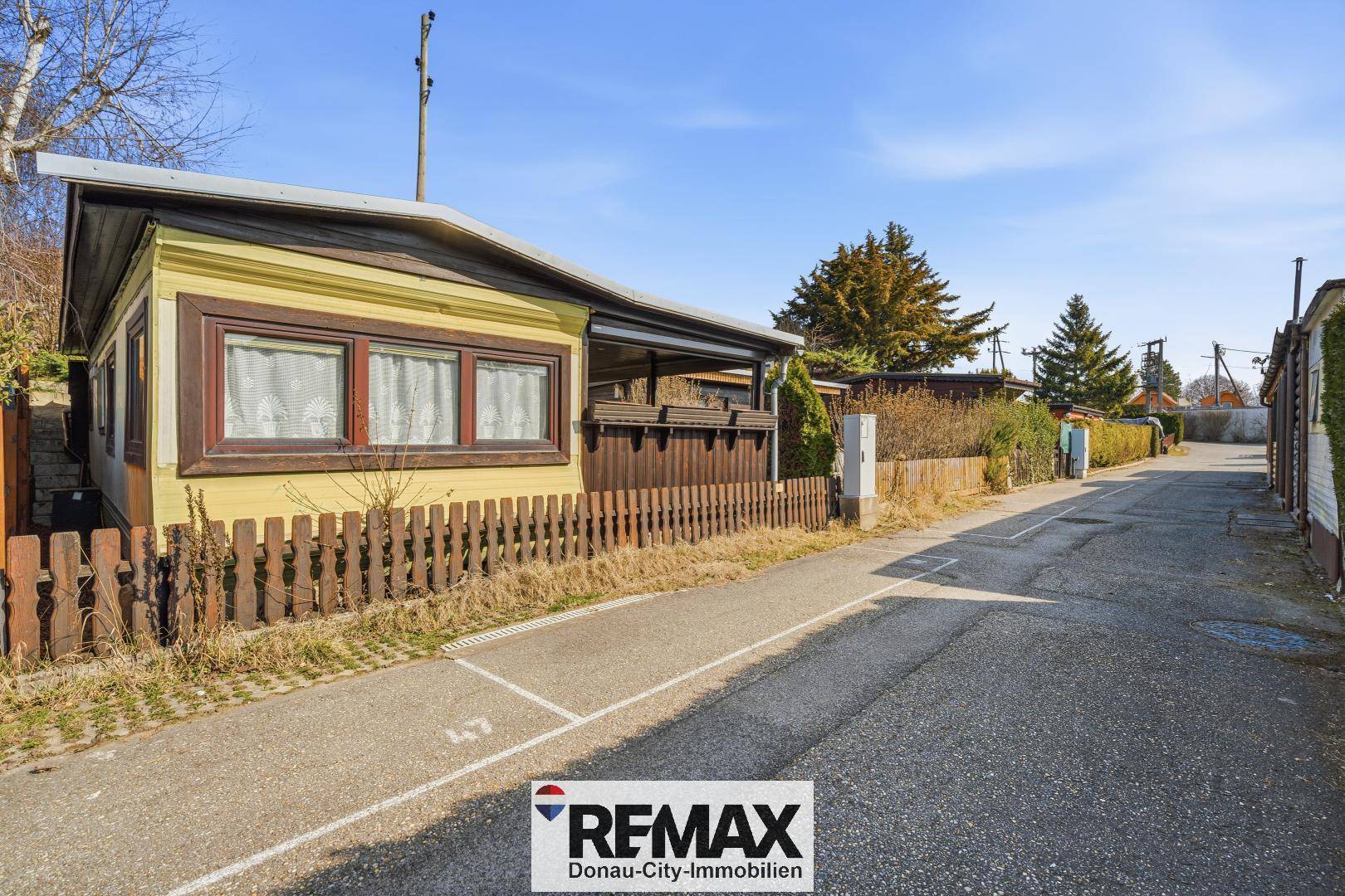Seitenansicht des kleinen gelben Hauses entlang einer ruhigen Straße in der Siedlung.