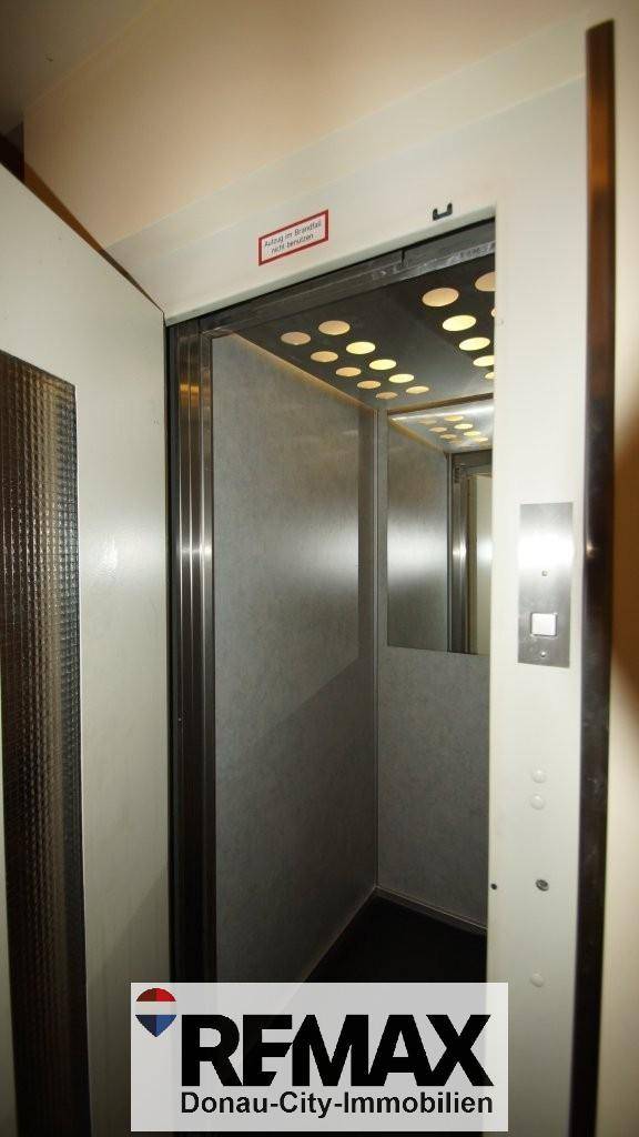 Innenansicht eines Aufzugs mit Spiegelflächen und Deckenbeleuchtung.