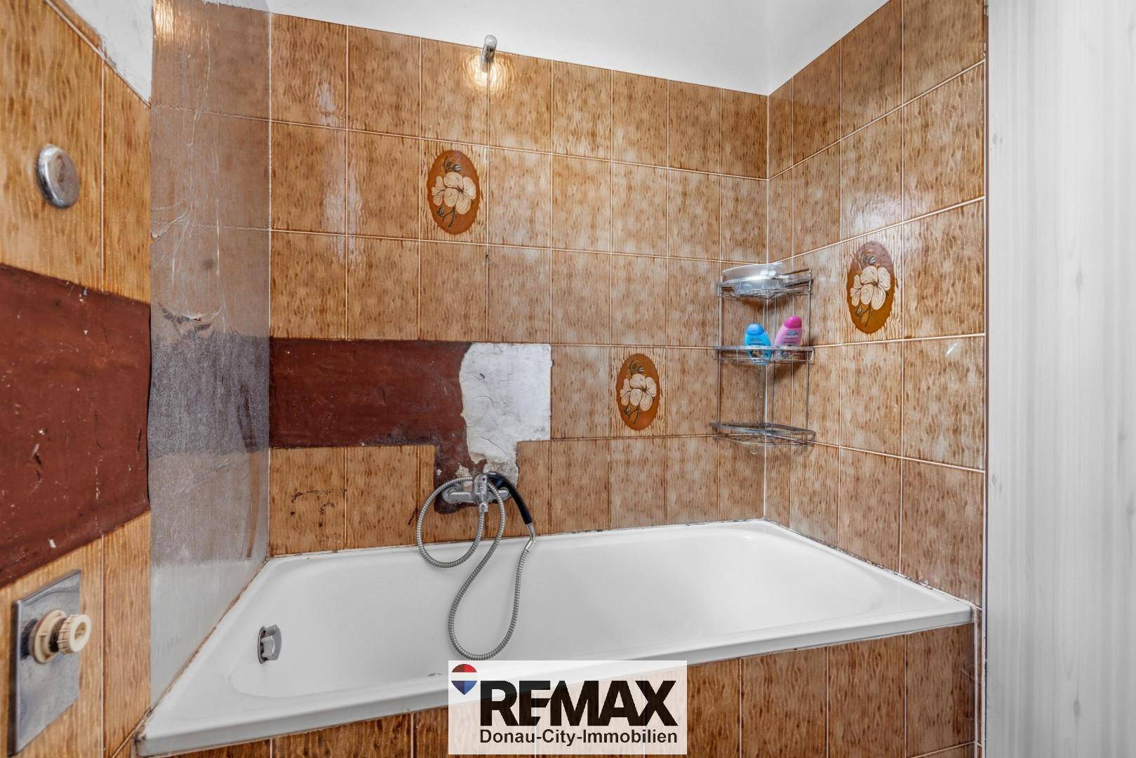 Badezimmer mit Badewanne und braunen Fliesen im Vintage-Stil, teilweise beschädigt.