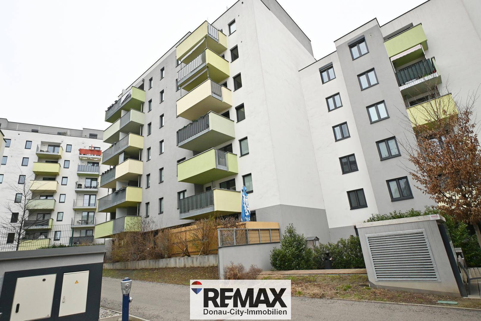 Ansicht eines modernen Wohngebäudes mit farbigen Balkonen und gepflegter Außenanlage.