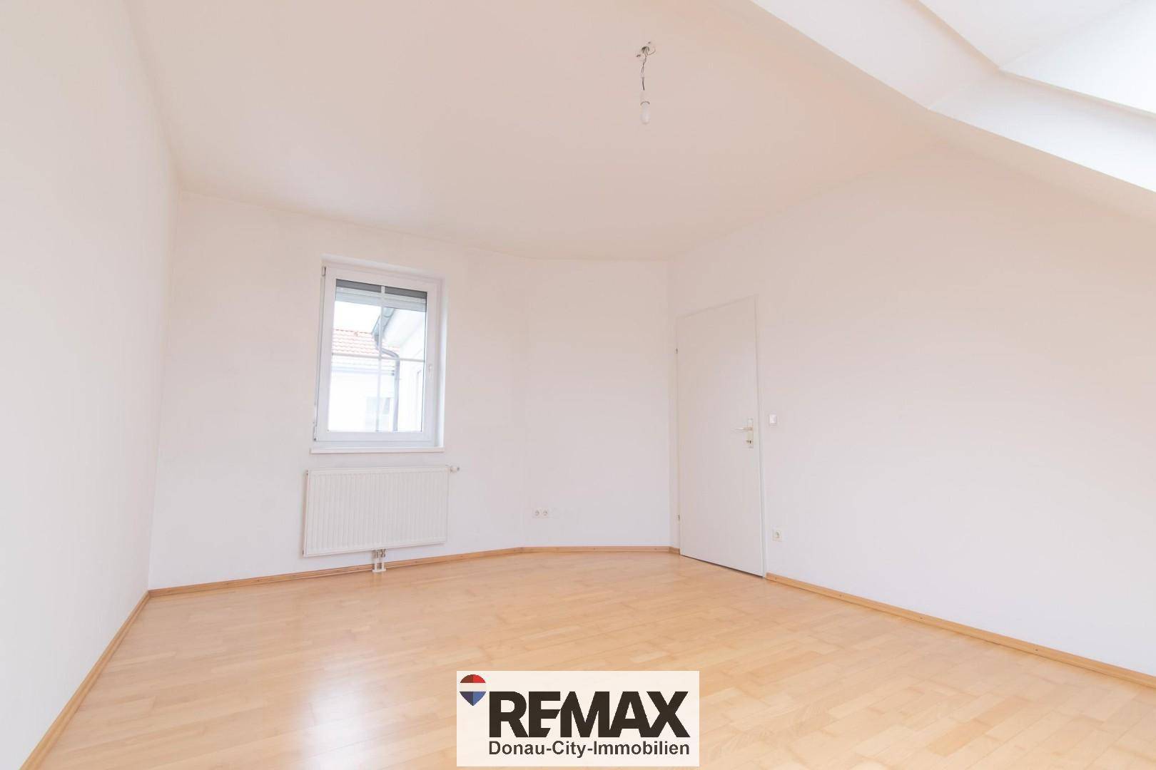 Heller, leerer Raum mit Holzboden und Fenster, ideal als Schlaf- oder Arbeitszimmer.