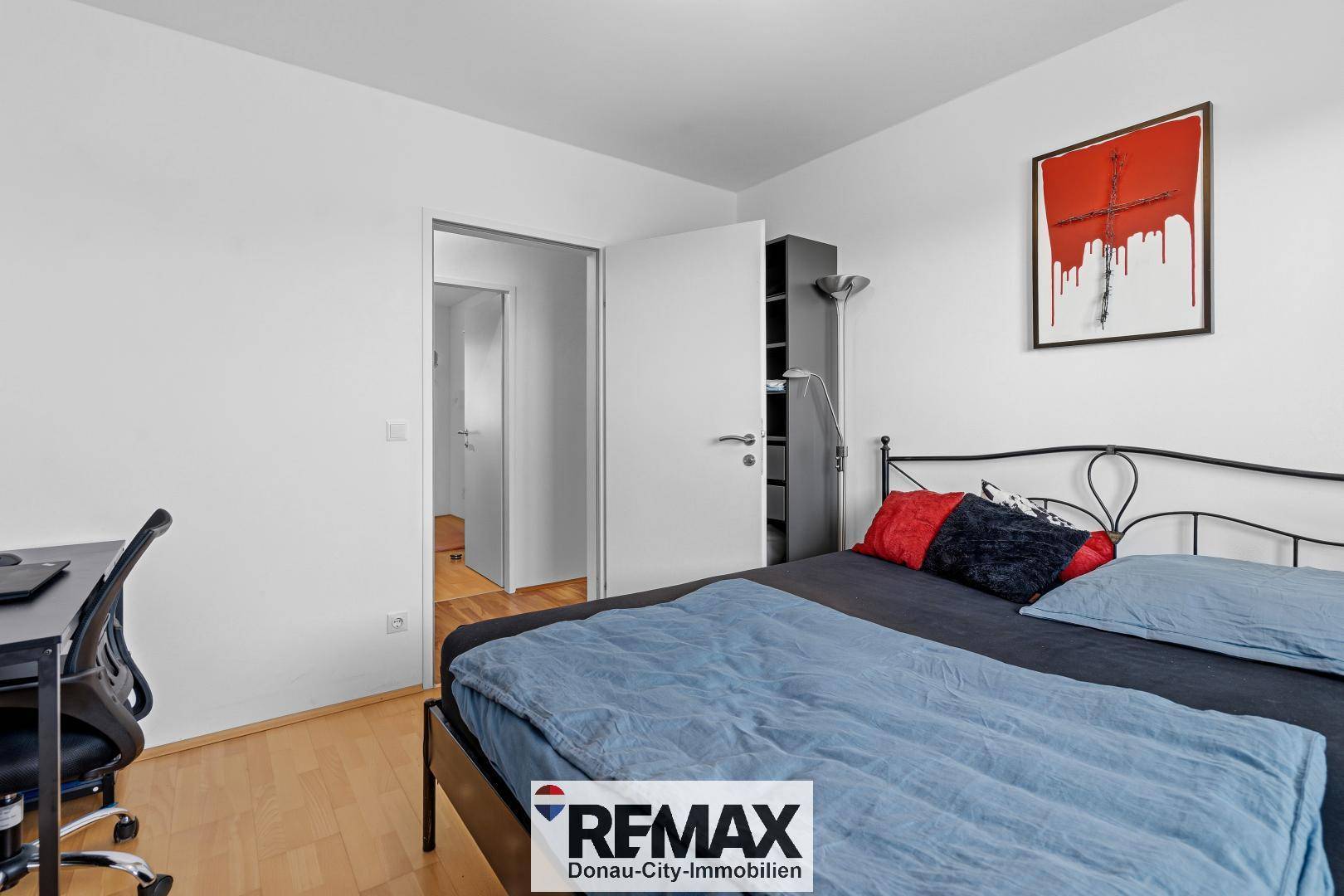 Helles Schlafzimmer mit Holzboden und Zugang zu einem weiteren Raum.
