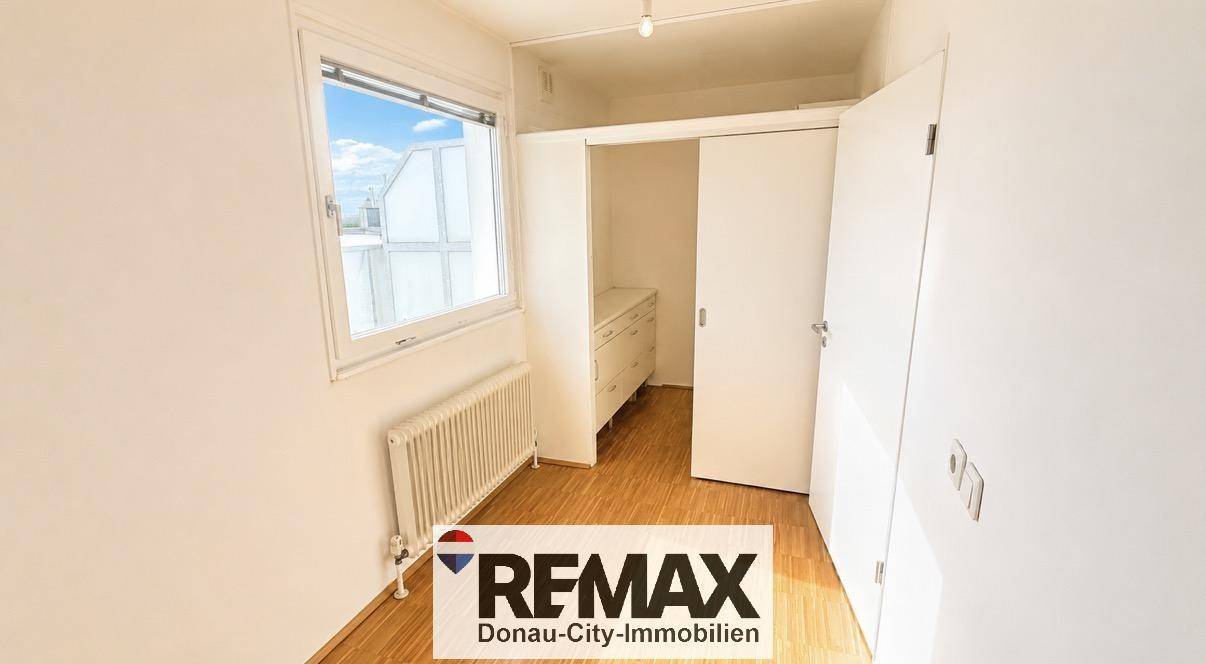 Kleines Schlafzimmer mit Fenster, Heizkörper und integriertem Schrankbereich.