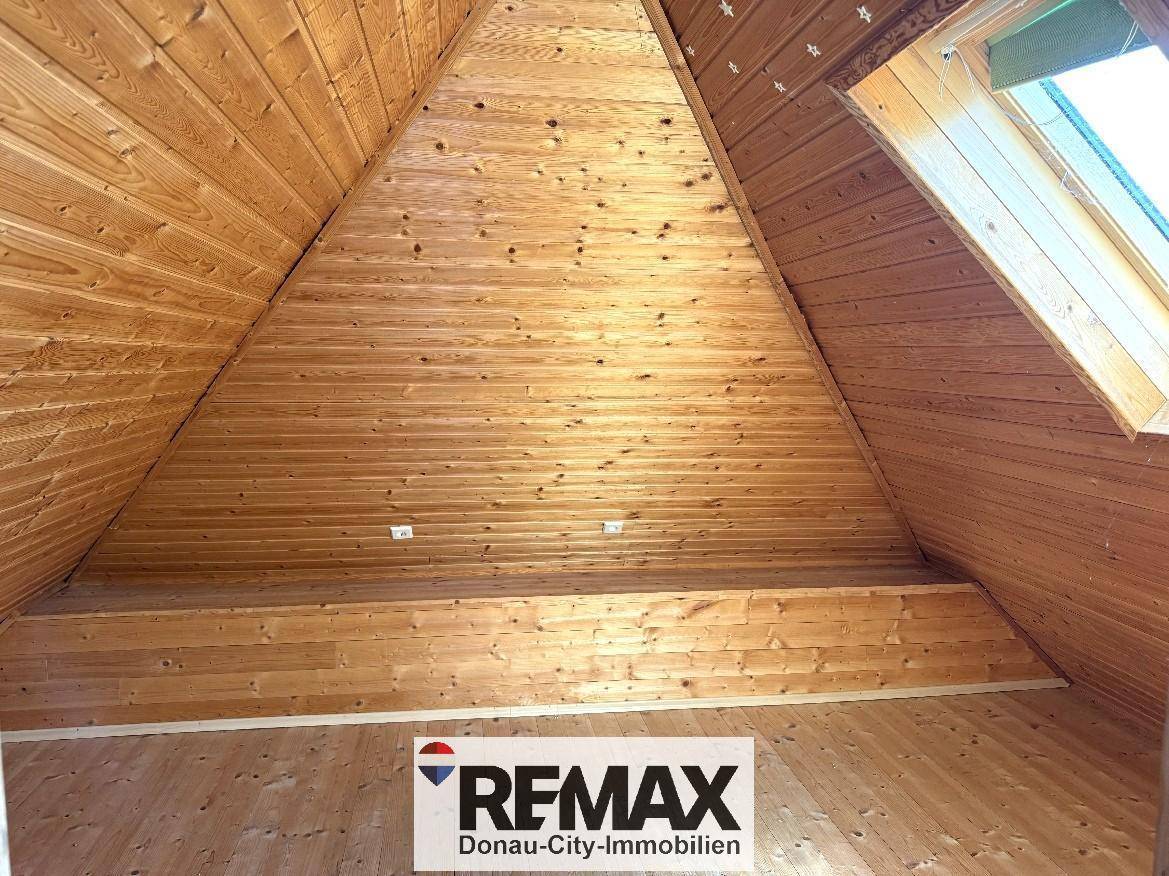 Ausgebauter Dachboden mit Holzverkleidung an Decke und Wänden sowie einem Dachfenster.