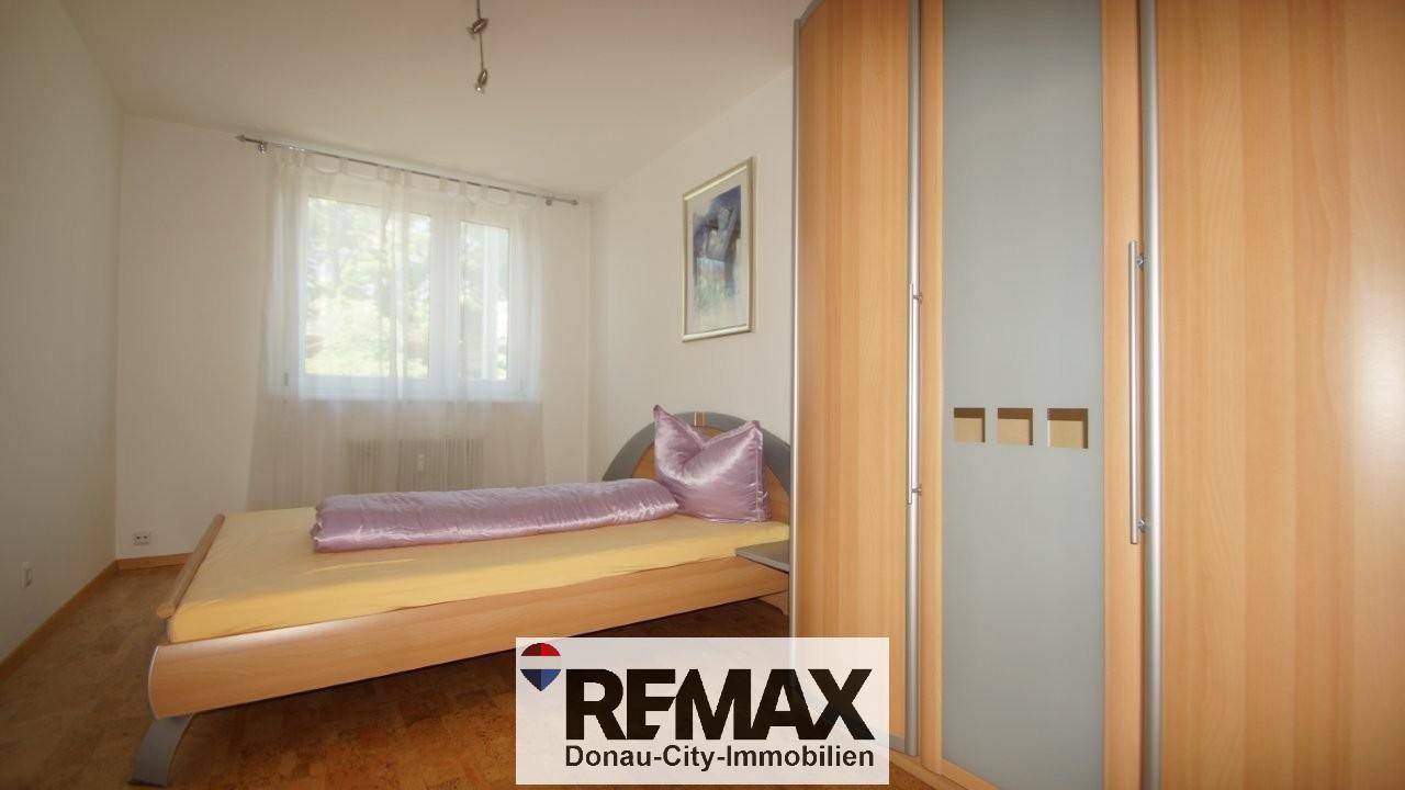 Schlafzimmer mit Bett, lila Bettwäsche und einem Kleiderschrank, bietet Komfort und Stauraum.