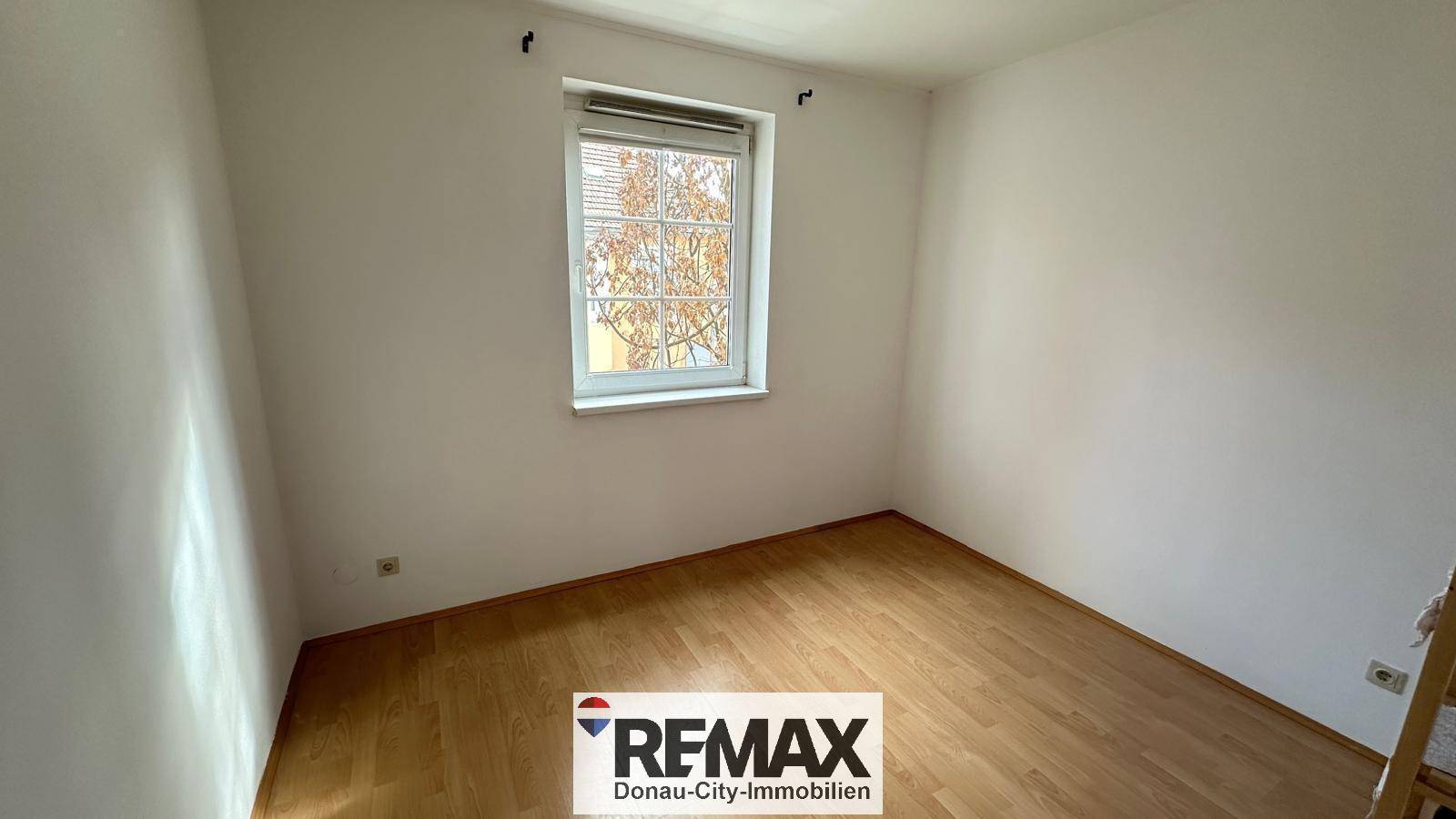 Helles Zimmer mit Parkettboden und einem Fenster, ideal als Schlaf- oder Arbeitszimmer.