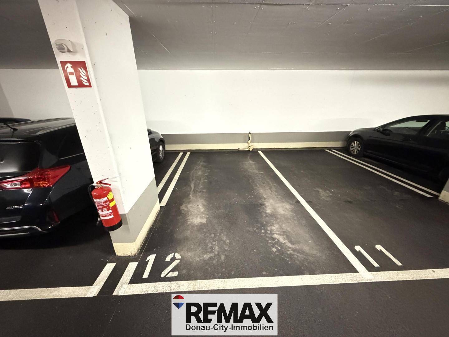Tiefgarage mit mehreren markierten Stellplätzen und geparkten Autos.