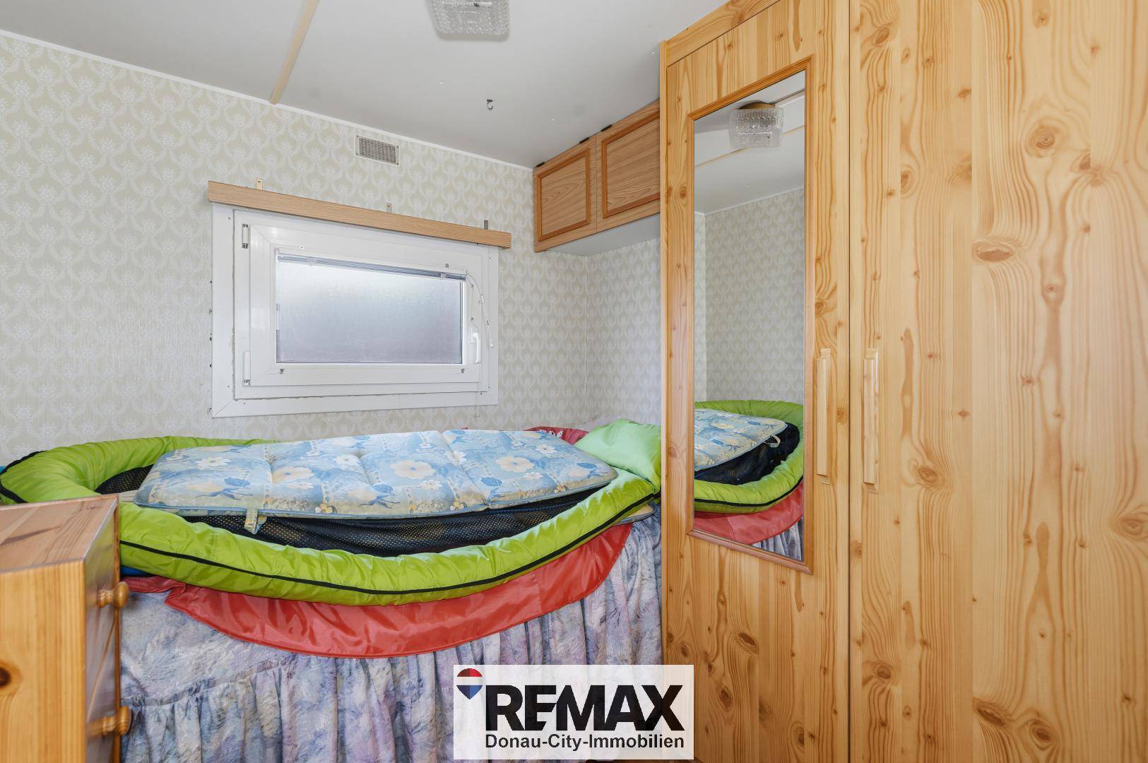 Gemütliches Schlafzimmer mit Einzelbett, Fenster und einem Kleiderschrank aus hellem Holz.