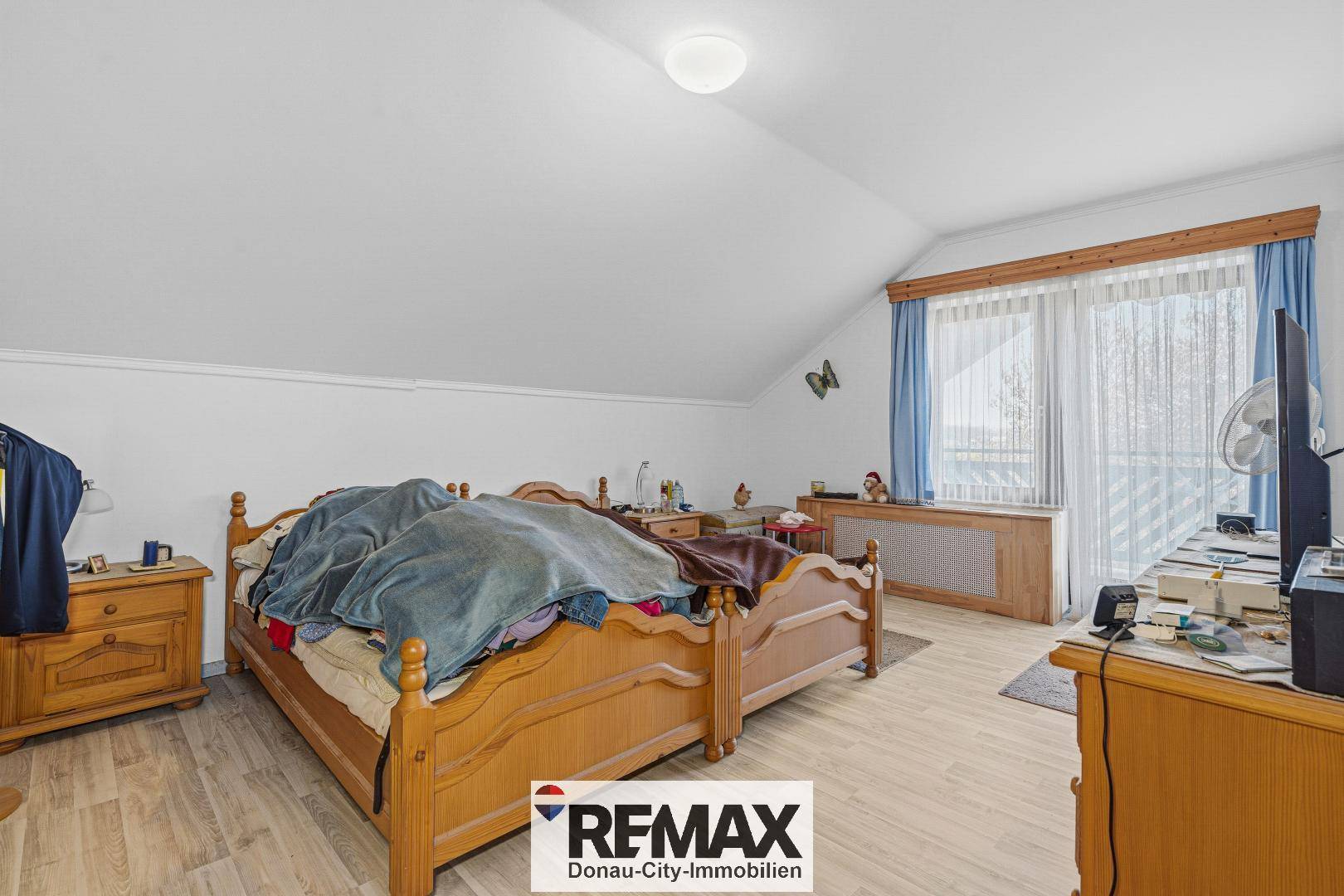Schlafzimmer im Dachgeschoss mit schräger Decke, Holzbett und hellem Laminatboden.