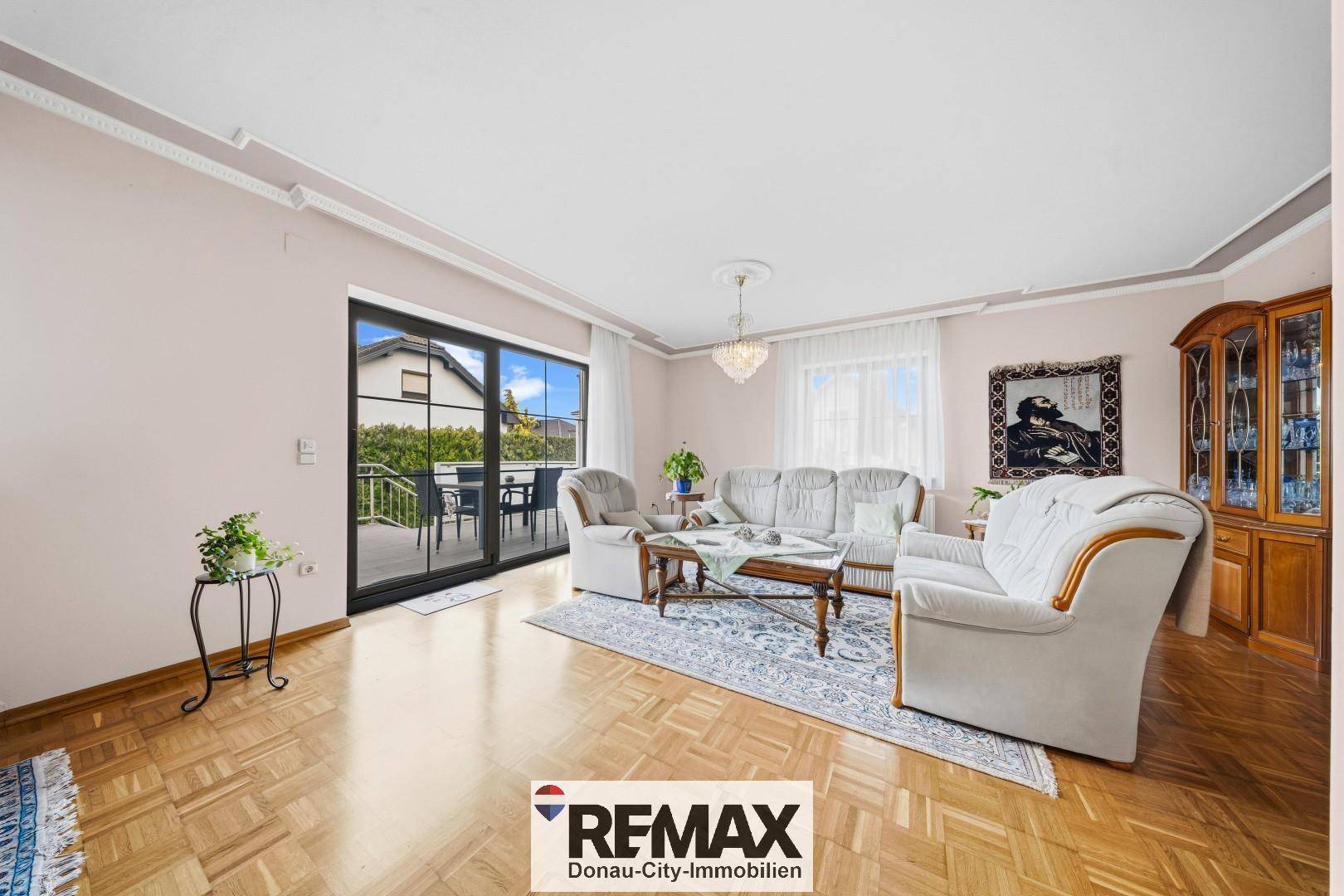 Helles Wohnzimmer mit Parkettboden, bequemen Sofas und Zugang zu einem Balkon.