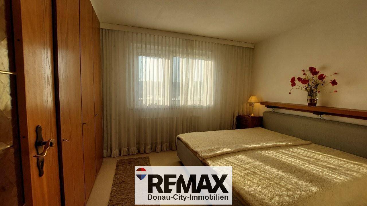 Helles Schlafzimmer mit Doppelbett, großem Fenster und Einbauschränken.