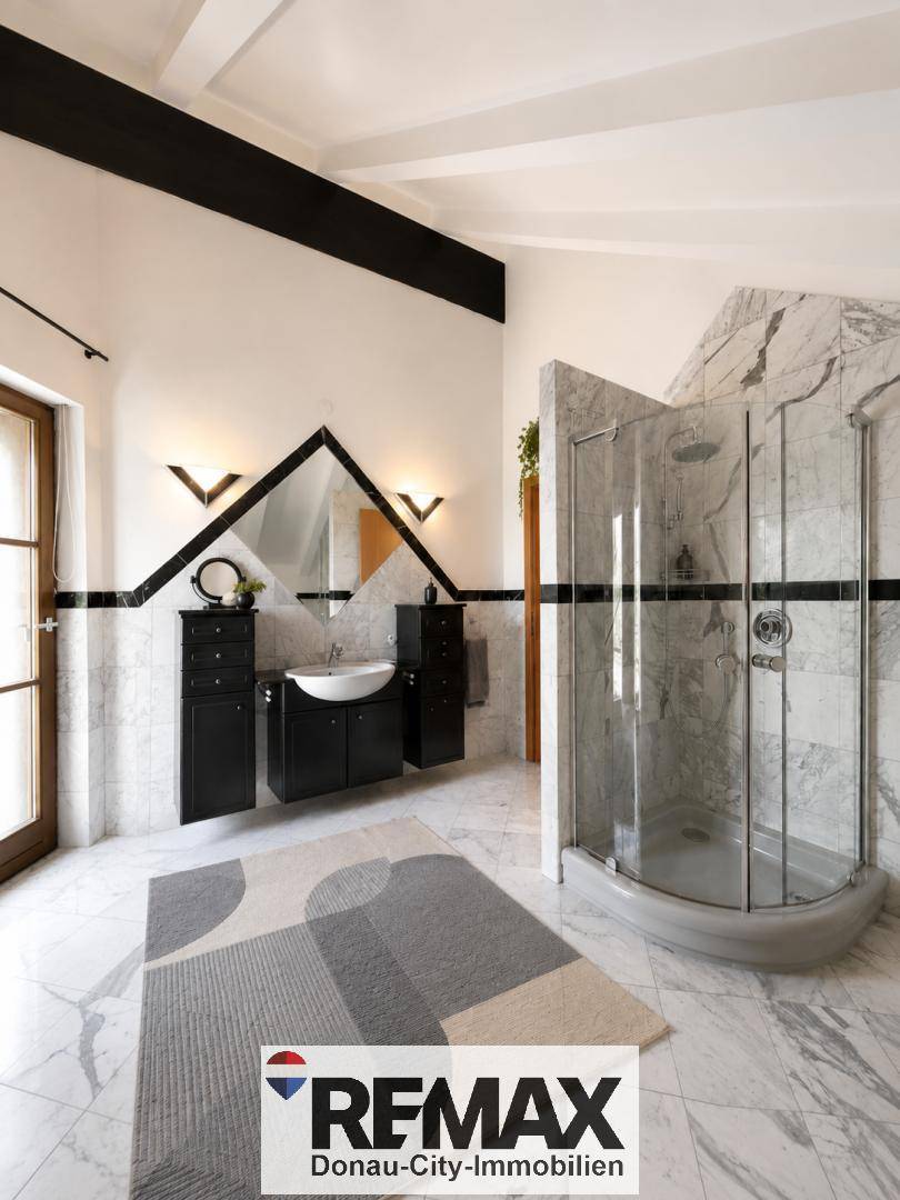 Modernes Badezimmer mit Marmorfliesen, einer Duschkabine und einem einzelnen Waschbecken, elegant gestaltet.