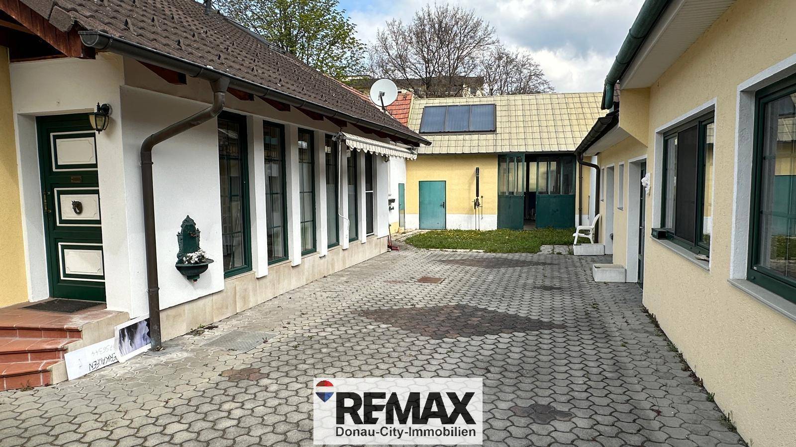 Innenhof mit gepflasterter Fläche zwischen den Gebäudeteilen und Solaranlage auf dem Dach.